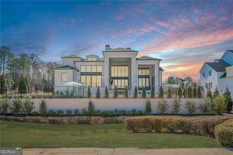 Exquisite Custom Estate on the First Tee at The Manor Golf & Country Club! Welcome to this stunning 6-bedroom, 6 full-bathroom, and 3 half-bathroom custom smart home, perfectly situated on the first tee in the prestigious gated community of The Manor Golf and Country Club in Milton. Designed with sophistication and comfort in mind, THIS HOME IS EQUIPPED WITH ACCESSIBILITY FEATURES TO ACCOMMODATE INDIVIDUALS WITH DISABILITIES. This meticulously upgraded residence boasts breathtaking golf course views, resort-style amenities, and state-of-the-art technology for an unparalleled living experience. Upon entering, youCOre greeted by a dramatic two-story great room featuring an 84C linear fireplace, custom lighting fixtures, and expansive quad sliders that fully open to the rear entertainment porch with automated screens and clear enclosure panelsCoperfect for seamless indoor-outdoor living. The gourmet kitchen is a chefCOs dream, complete with an oversized quartz island, Wolf, Dacor, and Miele appliances, full-sized wine refrigerator, additional two-drawer refrigerator, and a spacious dining area. A fully equipped catering kitchen includes a Wolf 6-burner gas range and double oven, Sub-Zero refrigerator, pot filler, second dishwasher, and second microwave, making hosting effortless. The two-story primary suite on the main level is a luxurious retreat, featuring an 84C linear fireplace, designer lighting, and a wall of windows with large sliding doors opening to a private patio overlooking the heated saltwater pool and golf course. The spa-inspired ownerCOs bath boasts a dual spa shower with steam, soaking tub, double vanities, his and her closets with built-insCoincluding a safeCoand private elevator access, along with two separate water closets. A floating three-level staircase, accented by a wall of windows, leads to the upper mezzanine, where youCOll find four spacious bedroom suites, each with walk-in closets, built-ins, and private baths. This level also includes a second laundry room and a versatile bonus room, ideal for a home office, playroom, or upstairs fitness area, complete with a half bath and private access to the second elevator. The enormous, finished terrace level, accessible via the floating staircase or elevator, features high ceilings, a bedroom and full bath, porcelain tile flooring, a billiard/game room with a wall of windows, and access to a side patio with a gas firepit. The theater room and a potential fitness area make this level perfect for recreation and relaxation. Step outside to your private backyard oasis, offering year-round outdoor entertaining with a stunning heated saltwater pool and spa, highlighted by four aqua spheres, LED lighting, a waterfall, fireplace, and travertine pavers, all enclosed with cable fencing for unobstructed golf course views. The two-story covered porch includes an outdoor kitchen, fireplace, and accessible lift, creating the ultimate retreat. Additional home features include a three-car side-entry garage with a car lift to accommodate a fourth vehicle, two EV chargers, and a professionally coated floor. A circular driveway and side driveway provide ample parking for guests. The home is also equipped with a generator, seven heating and air systems, two tankless water heaters, three fireplaces, two outdoor firepits, and even an outdoor warm-water faucet for pet bathing. Residents of The Manor Golf & Country Club enjoy world-class amenities, including indoor and outdoor pools, tennis courts, two clubhouses, a fitness center, fine dining, and an 18-hole Tom Watson-designed golf course. The home is conveniently located near top-rated schools, shopping, dining, and entertainment, with easy access to GA-400. This one-of-a-kind estate offers the perfect blend of luxury, comfort, and convenience. Schedule your private showing today!