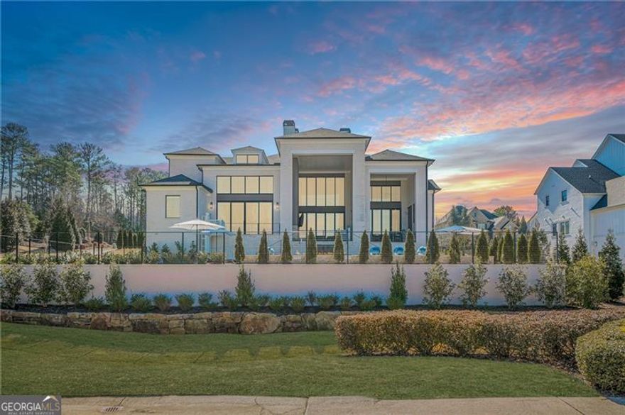Exquisite Custom Estate on the First Tee at The Manor Golf & Country Club! Welcome to this stunning 6-bedroom, 6 full-bathroom, and 3 half-bathroom custom smart home, perfectly situated on the first tee in the prestigious gated community of The Manor Golf and Country Club in Milton. Designed with sophistication and comfort in mind, THIS HOME IS EQUIPPED WITH ACCESSIBILITY FEATURES TO ACCOMMODATE INDIVIDUALS WITH DISABILITIES.  This meticulously upgraded residence boasts breathtaking golf course views, resort-style amenities, and state-of-the-art technology for an unparalleled living experience. Upon entering, youCOre greeted by a dramatic two-story great room featuring an 84C linear fireplace, custom lighting fixtures, and expansive quad sliders that fully open to the rear entertainment porch with automated screens and clear enclosure panelsCoperfect for seamless indoor-outdoor living. The gourmet kitchen is a chefCOs dream, complete with an oversized quartz island, Wolf, Dacor, and Miele appliances, full-sized wine refrigerator, additional two-drawer refrigerator, and a spacious dining area. A fully equipped catering kitchen includes a Wolf 6-burner gas range and double oven, Sub-Zero refrigerator, pot filler, second dishwasher, and second microwave, making hosting effortless.  The two-story primary suite on the main level is a luxurious retreat, featuring an 84C linear fireplace, designer lighting, and a wall of windows with large sliding doors opening to a private patio overlooking the heated saltwater pool and golf course. The spa-inspired ownerCOs bath boasts a dual spa shower with steam, soaking tub, double vanities, his and her closets with built-insCoincluding a safeCoand private elevator access, along with two separate water closets.  A floating three-level staircase, accented by a wall of windows, leads to the upper mezzanine, where youCOll find four spacious bedroom suites, each with walk-in closets, built-ins, and private baths. This level also includes a second laundry room and a versatile bonus room, ideal for a home office, playroom, or upstairs fitness area, complete with a half bath and private access to the second elevator.  The enormous, finished terrace level, accessible via the floating staircase or elevator, features high ceilings, a bedroom and full bath, porcelain tile flooring, a billiard/game room with a wall of windows, and access to a side patio with a gas firepit. The theater room and a potential fitness area make this level perfect for recreation and relaxation. Step outside to your private backyard oasis, offering year-round outdoor entertaining with a stunning heated saltwater pool and spa, highlighted by four aqua spheres, LED lighting, a waterfall, fireplace, and travertine pavers, all enclosed with cable fencing for unobstructed golf course views. The two-story covered porch includes an outdoor kitchen, fireplace, and accessible lift, creating the ultimate retreat. Additional home features include a three-car side-entry garage with a car lift to accommodate a fourth vehicle, two EV chargers, and a professionally coated floor. A circular driveway and side driveway provide ample parking for guests. The home is also equipped with a generator, seven heating and air systems, two tankless water heaters, three fireplaces, two outdoor firepits, and even an outdoor warm-water faucet for pet bathing. Residents of The Manor Golf & Country Club enjoy world-class amenities, including indoor and outdoor pools, tennis courts, two clubhouses, a fitness center, fine dining, and an 18-hole Tom Watson-designed golf course. The home is conveniently located near top-rated schools, shopping, dining, and entertainment, with easy access to GA-400. This one-of-a-kind estate offers the perfect blend of luxury, comfort, and convenience. Schedule your private showing today!