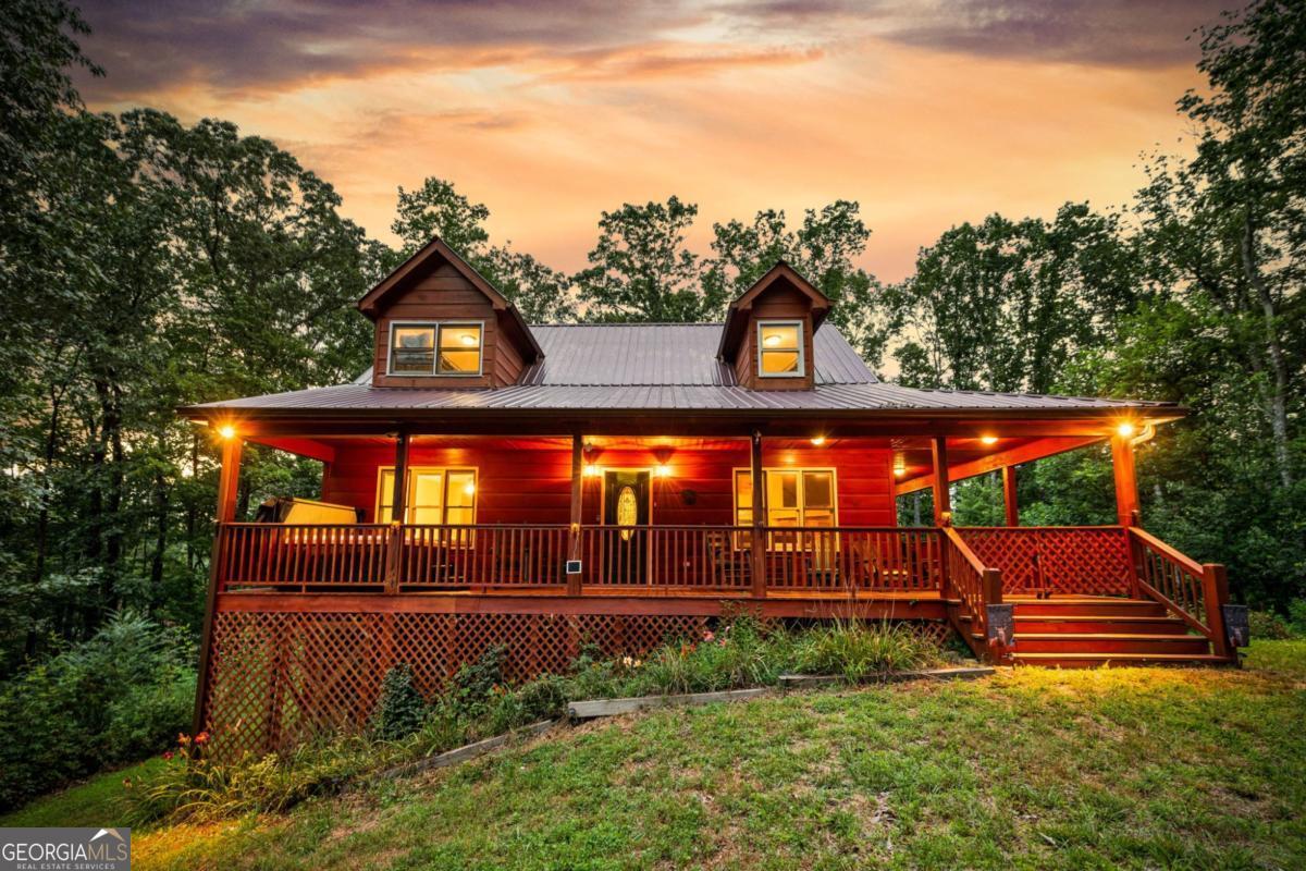 Escape to your own mountain retreat in the heart of Ellijay, an ideal opportunity for both personal enjoyment and investment potential. Nestled in the scenic North Georgia mountains, this charming cabin offers the perfect blend of rustic character and modern comfort. A spacious wrap-around porch welcomes you with panoramic views, while the open-concept interior features soaring vaulted ceilings, a cozy stone fireplace, and oversized windows that flood the home with natural light. The kitchen and living areas flow seamlessly, creating a warm, inviting space for gatherings. The private master suite includes an en-suite bath, and additional guest accommodations provide plenty of room for family or renters. Outside, a private deck overlooks the beautifully landscaped backyard-perfect for grilling, entertaining, or simply relaxing in nature's embrace. Sold fully furnished and turn-key, this property is ready for immediate use as a vacation home or short-term rental. With its desirable location, strong vacation appeal, and versatile layout, it offers the perfect balance of mountain living and income-producing potential.