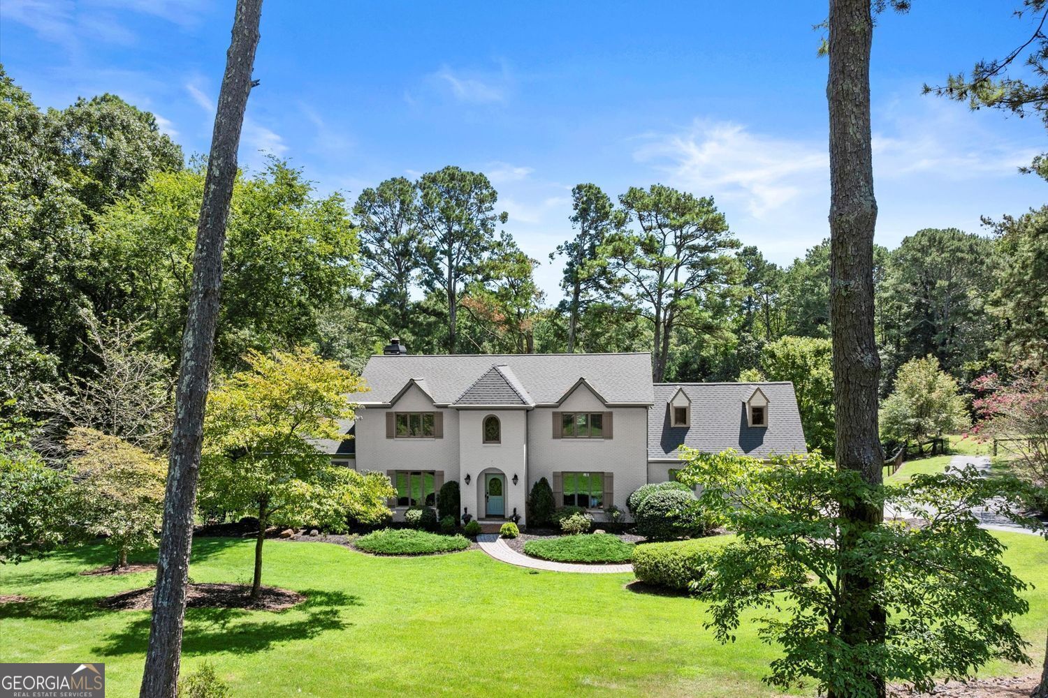 Idyllic 12 Acre Equestrian Retreat with Alpharetta Address and Low Cherokee County Taxes - Just Minutes from Milton and Downtown Alpharetta! Welcome to your dream farmstead, where luxury living meets rural charm on this stunning gated property located in sought-after E. Cherokee County-with the added benefit of an Alpharetta address and lower taxes! Tucked away just minutes from the heart of Milton and downtown Alpharetta, this one-of-a-kind estate offers a tranquil lifestyle with unbeatable convenience. Spanning open and fenced pastures, this property is a true haven for horse lovers and hobby farmers alike. The 5-stall barn includes a wash stall, tack room, full hay loft, and adjacent riding ring. Additional features such as a run-in shed, chicken coop, and dedicated garden with water access make this a fully functioning and well-equipped farm. This charming painted brick home blends rustic character with upscale touches. The main level boasts vaulted ceilings with exposed wood beams, Mexican tile flooring, and casement windows that flood the home with natural light and showcase breathtaking pastoral views. Entertain with ease in the expansive dining room or the chef's kitchen featuring marble countertops, double Dacor ovens, a 5-burner gas range, LG French door refrigerator, and charming antique hutch centerpiece. The main-level owner's suite is a true sanctuary with panoramic views, spa-like bath, and a custom walk-in closet with attached laundry. Upstairs, a secondary owner's suite, two additional bedrooms, an office, and cedar closet offer space and versatility for guests or family. The finished basement includes a full bath and flex space perfect for a gym, studio, or craft room, while the workshop with overhead door and utility sink is a dream for any handyman. Outdoor living is elevated with a large deck, covered patio, and plenty of space for a future pool-all overlooking rolling green pastures and a peaceful creek at the rear of the property. Enjoy comfort and efficiency with 3 HVAC systems, 2 water heaters, a private well, and 220V power in the garage. The gated entry and guest notification alert system provide added security and peace of mind.