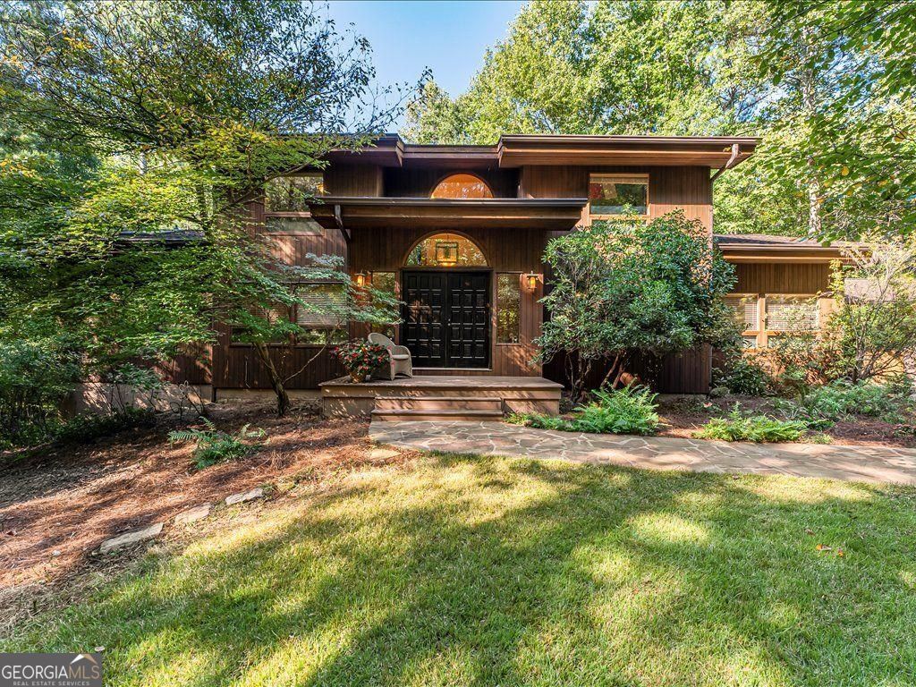 Private retreat, 4-bedroom/3.5-bath home with pool and finished terrace level - Minutes from Milton's vibrant shops, dining, and top-rated schools. Just over the Cherokee line, so enjoy lower taxes. Soaring Cathedral ceilings and oversized windows showcase the lush landscape of this two-acre lot. Current owner is a renowned Georgia Native Plant expert- her years of hard work provide seasonal change and color to enjoy year-round, attracting an abundance of birds, butterflies, and other local fauna. Enjoy views of your pool and spa from the 80+ ft composite deck that stretches the entire back of the home, offering plenty of space for outdoor dining, lounging, or hosting large gatherings with spectacular views of the treetops. Main level- enjoy oversized dining, living room, and great room, all with high wooded beam ceilings. Kitchen and family room connected for both relaxation and entertaining, overlooking the deck. Primary suite on the main level with a spacious bathroom and views of the backyard oasis. Upstairs, two generously sized bedrooms, a full bath, and a fantastic loft area perfect for a study nook or teen space. The finished terrace level offers endless possibilities with a very cool bar for entertaining, a full bath with shower, a dedicated art studio, and a super hip music room that could also be a teen bedroom or home office. The terrace level has an abundance of shelved storage spaces. 3-car garage, oversized driveway area for extra parking. This house is a true gem, with so much space, privacy, and light. You are going to love living here!