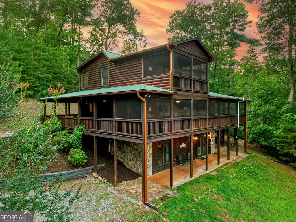 Stunning mountain cabin offers the perfect mix of year-round long-range views, privacy, and convenience to everything North Georgia has to offer. A huge wraparound porch, screened-in porch, and hot tub deck provide endless opportunities to relax and take in the scenery, while the large yard is ideal for kids or pets to roam. Inside, the vaulted great room showcases a floor-to-ceiling stone gas log fireplace, and the spacious kitchen features granite countertops, stainless appliances, and a cozy dining nook. The main level includes a large bedroom and full bath with double vanities plus a laundry closet for convenience. A beautiful log staircase leads to a generous loft with a sectional and TV area, along with a master suite complete with private covered porch, walk-in closet, jetted stone-surround tub, and walk-in stone shower. The finished terrace level is built for fun and entertaining, with another TV gathering area, pool table, foosball table, large bedroom, and full bath. Offered fully furnished and turnkey, this is an exceptional opportunity for a full-time residence, mountain getaway, or investment property.