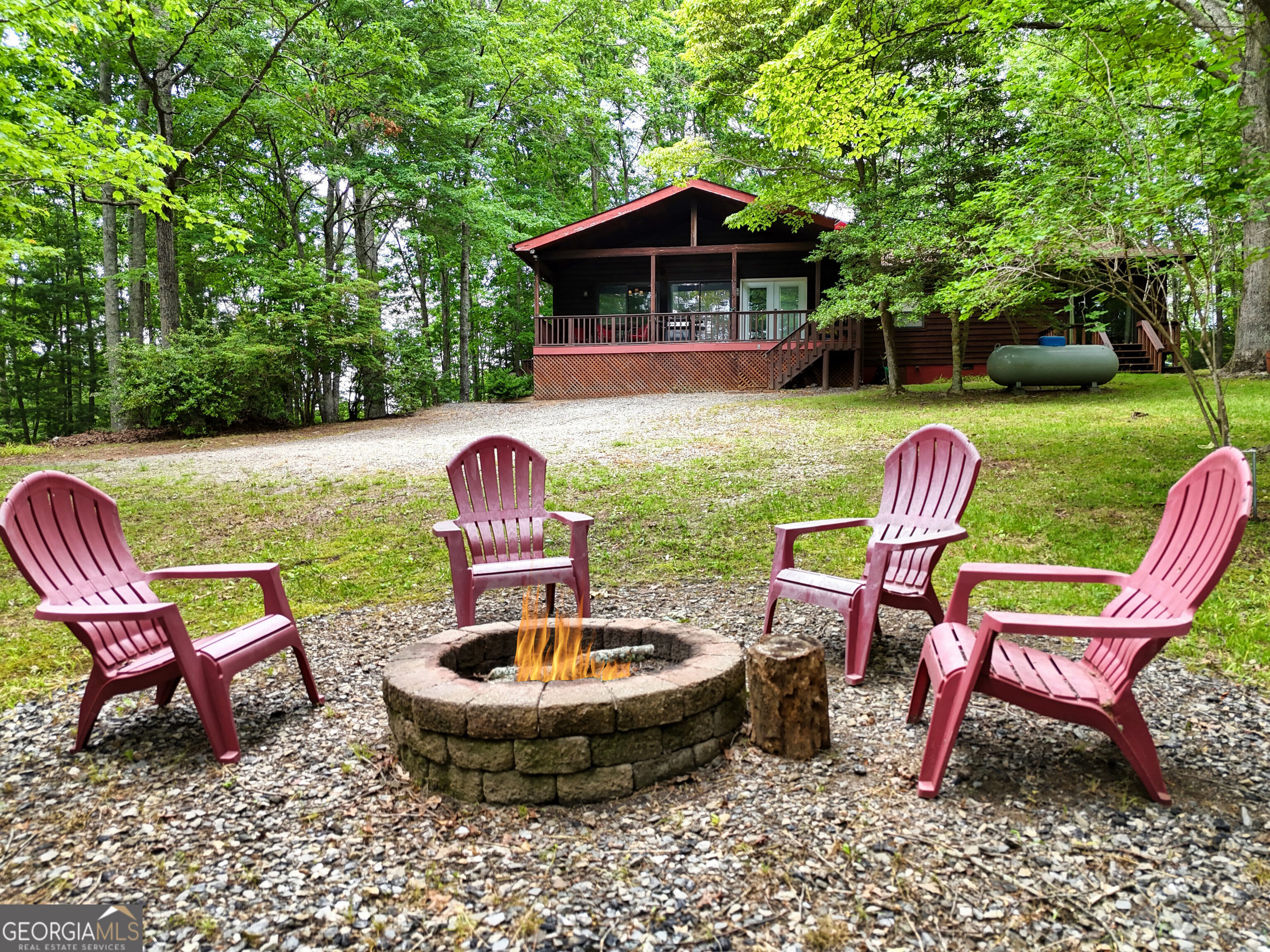 2BR/2BA Rustic Ranch Near Downtown Blairsville. Charming mountain-style ranch featuring a vaulted ceiling great room where a striking floor-to-ceiling Tennessee fieldstone wall creates a natural division between the spacious living area and kitchen. The open-concept layout features a spacious living room, dining area, leading to a bright office nook with a large skylight and outdoor access. The split floor plan ensures privacy, featuring a spacious master with a free-standing fireplace and a walkout deck. The second bedroom also has access to a private deck, complemented by a bonus room. Enjoy the huge screened back porch ideal for entertaining, complete with a pool table, and plenty of room for memorable family gatherings. Fire pit surrounded with hardwood, seasonal mountain views & cool mountain breezes. Situated on a level lot with end-of-road privacy. Just minutes from downtown Blairsville, Old Union & Butternut Creek Golf Course, shopping, and healthcare. Fully furnished and move-in ready, and ideal for full-time living or a weekend escape to the North Georgia Mountains.