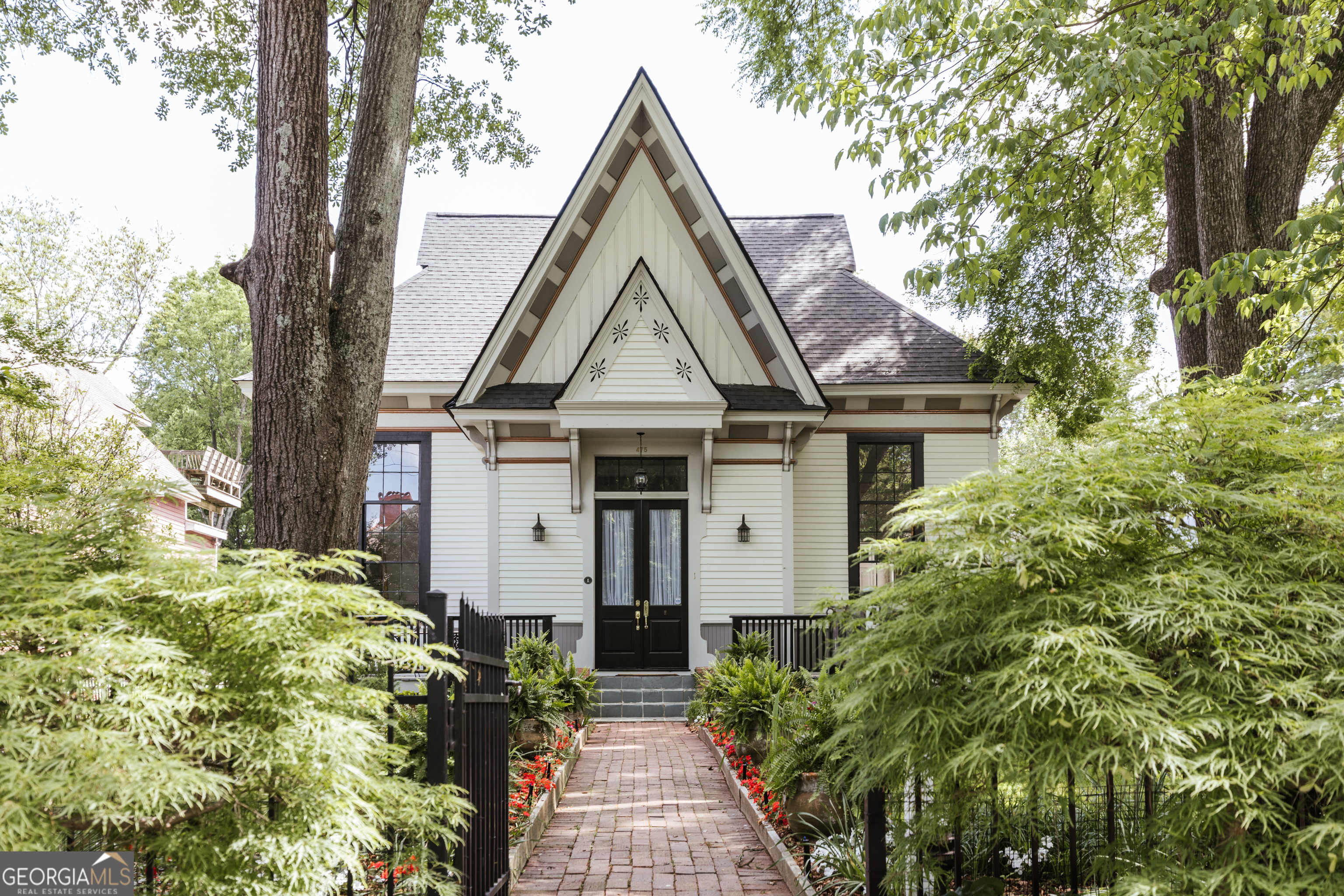 Incredible opportunity to own a beautifully restored Gothic Revival home in Cobbham Historic District. 475 Meigs Street is an Athens icon with one-of-a-kind architectural features recognizable by anyone who has spent even a short amount of time in the Classic City. The original property comprising half of a city block served as one of Athens' first schools, The Meigs Street School, until 1918. Many of the original structures still stand today and have been converted into residences. The home, constructed c. 1873, is sited a notable distance from the street which allows a delightful fenced front yard - a gardener's paradise with many mature trees, perennials, and a sizable water feature with Koi fish. There are many areas of the yard to entertain friends and family, and you can wave to passersby who are walking to Downtown Athens or the multiple restaurants in between. Ascending the front steps, you reach the deck that flanks the French Doors. Upon entry, a breathtaking view of the Greatroom enveloped in natural lighting courtesy of four restored, triple-hung windows. Heart of pine flooring runs throughout the main level of the home with exception to the oak inlay at the center of the Greatroom and Brazilian Cherry in the Primary Suite. Wide baseboards, gorgeous moldings, and stately columns are a testament to the craftsmanship of yesteryear. The floorpan lends itself to entertaining and dinner parties with a dining area that seats twelve. The kitchen features ample, freshly painted custom cabinetry, stainless steel appliances including a double wall oven, granite countertops, and another gorgeous, triple-hung window. The Primary Suite features Brazilian Cherry floors and a spacious ensuite bathroom with wide vanity, Jacuzzi tub, and separate shower. Through the ensuite bathroom is the walk-in closet complete with custom closet system and eye-level windows spanning the length of the outside wall. Two secondary bedrooms, one featuring a custom loft, share a hall bathroom. The laundry room has a wall of storage shelves perfect for your sundries and houseplants. 475 Meigs Street consists of three unique living spaces. The main level consists of three bedrooms, two bathrooms, and has soaring ceilings. Upstairs, you will find the Mother-In-Law Suite featuring ample living space, two bedrooms, a full kitchen, full bathroom, and laundry. Multiple skylights and clerestory windows bring in the sunlight while also allowing extra privacy. Ample built-in storage and closets in this suite to boot. An adorable cottage located in the side yard has a studio layout to include a full kitchen and bathroom plus a lofted bed. The current owners have experienced great success with Airbnb and long-term tenants occupying the guest suites should a new owner wish to live on the main level and generate passive income. Need more storage? The 500+ square foot unfinished basement is perfect for hiding your excess possessions, creating a man-cave, or workshop. This is the epitome of In-Town Athens living - walk, roll, or scoot to all the excellent dining and shopping options on the Prince Avenue Corridor, Bottleworks, and Downtown Athens. The University of Georgia's historic North Campus is just a stone's throw away. Schedule your private tour today!