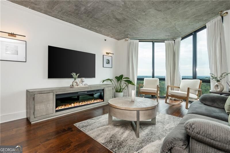 A true standout at The Concorde, this one-of-a-kind one bedroom residence redefines what condo living in Buckhead can be. Thoughtfully redesigned with a modern open concept layout, this home is the only 1-BR unit in the building to feature a full kitchen island, creating a seamless flow between cooking, dining, and entertaining. The kitchen itself is a showpiece, with dual tone shaker cabinetry, sleek hardware, open wood shelving, a subway tile backsplash, a built-in wine fridge, and elevated light fixtures that add warmth and sophistication to the space. The exposed concrete ceilings with visible ductwork give the home an industrial edge that feels both modern and authentic, something rarely found in this building. The bright and airy living room is framed by floor to ceiling windows showcasing one of the most desirable views in The Concorde, a sweeping west facing panorama over Buckhead's lush tree canopy that glows at sunset. The spacious bedroom enjoys the same natural light and skyline views, complemented by a large walk-in closet and beautiful hardwood floors that run throughout the home. The renovated bathroom features a walk-in subway tile shower, designer floor tile, and striking gold hardware that ties the space together with timeless style. Additional highlights include in-unit laundry with a washer and dryer, elevated lighting throughout, and thoughtfully designed storage solutions. Residents of The Concorde enjoy 24 hour concierge service, a resort style pool, tennis courts, a state of the art fitness center, a private dog park, and secure gated parking, all in one of Buckhead's most convenient and walkable locations just moments from the Shops of Buckhead, Whole Foods, and some of Atlanta's best dining and nightlife. With its distinctive layout, designer finishes, and incredible west facing views, this condo represents a rare opportunity to own a truly unique home in one of Buckhead's most established high rises.