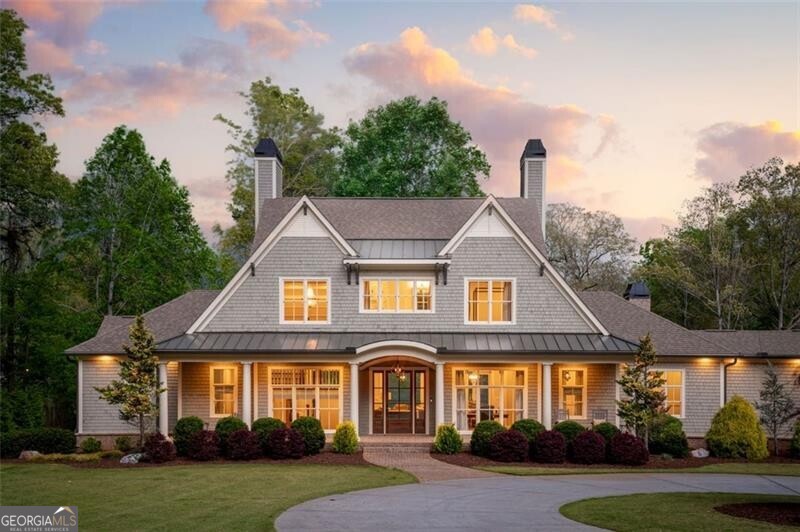 Welcome to a world of ultimate relaxation and sophistication in this exquisite Nantucket-inspired estate, nestled in Cumming, Georgia, on the most desirable part of Lake Lanier! Set gracefully on 3.7 acres, featuring over 200 feet of pristine shoreline, this stunning home built in 2017, captures the essence of timeless elegance and coastal charm. With breathtaking views of the lake's sparkling waters greeting you from nearly every corner, this residence offers a perfect blend of exquisite craftsmanship, comfort and luxurious living, ideal for those who crave both quiet moments and lively gatherings. As you step into this heirloom home, you're welcomed by an open, airy layout that feels both inviting and impressive. The estate boasts seven beautifully designed bedrooms, each crafted to feel like a cozy retreat. The main-floor Primary suite is a true gem, offering a peaceful escape with soft, elegant touches and windows that flood the room with natural light and gorgeous lake views. For guests, a private suite is tucked away over the garage and provides a warm, intimate space to unwind. And for those fun-filled occasions, a whimsical bedroom with eight bunk beds brings a playful, charming feel. Elevator ready makes access to each level a breeze! At the heart of this entertainer's dream lies a chef's kitchen that's nothing short of spectacular. Outfitted with top-notch Thermador appliances and thoughtful details, it's a space that sparks joy for anyone who loves to cook or host. Right around the corner, a handy butler's kitchen makes throwing parties a breeze, keeping everything running smoothly while adding a touch of understated class. Whether it's a quiet dinner gathering or a big celebration, these spaces make every moment feel special. Step outside to the covered verandas, where you can relax in the shade and breathe in the lake views. The sparkling saltwater pool catches the sunlight just right, inviting you to lounge or splash around on warm afternoons. For those who love a bit of activity, a private sport court adds a fun twist, while dedicated oversized parking makes for the ultimate out of the way storage for large vehicles, motor coach or a boat trailer. Downstairs, the finished walk out terrace level offers a world of possibilities. With tall 10-foot ceilings, it feels spacious and grand, blending the comfort of indoors with the beauty of the outdoors. The true treasure of this estate is its private double-slip dock, resting along year-round deep waters that call you to fully embrace lake life. Picture lazy mornings by the water, afternoons boating with friends, or quiet evenings watching the sunset paint the sky. This isn't just a house-it's a lifestyle wrapped in sophistication, where every detail, from the Nantucket-inspired design to the thoughtful craftsmanship, feels like a nod to something extraordinary. On Lake Lanier, this home stands out as a rare find, offering not just a place to live but a legacy of memories, where luxury and warmth weave together to create something truly unforgettable.