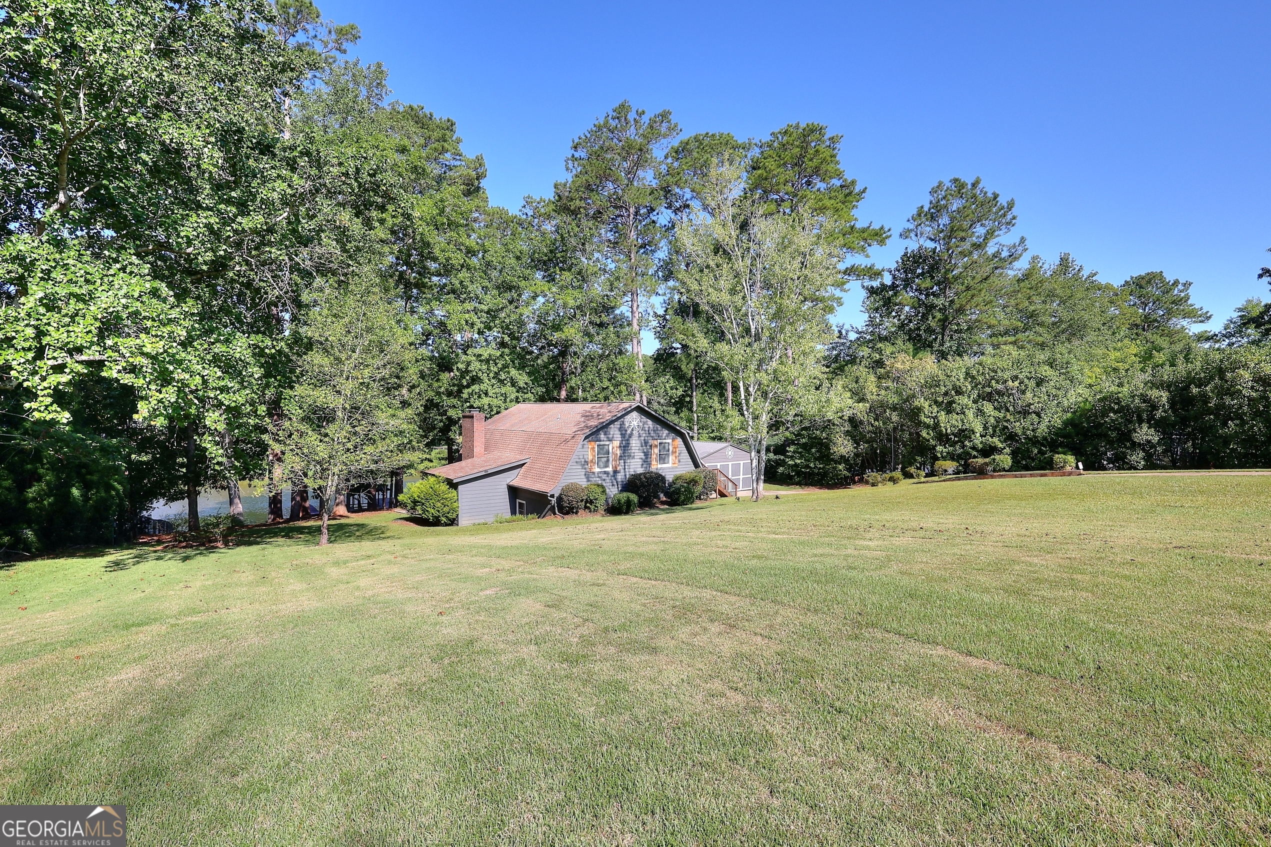 This charming Lake Sinclair Home will make you want to sing and if this home were a song, it would be titled "I love her because I love to fish" or "Sitting on the dock Watching the Sun Fade Away" This adorable Lake Sinclair property is the perfect blend of comfort, space, and waterfront fun. Tucked away on a quiet part of the lake, this move-in ready home features 3 oversized bedrooms, 2 spacious bathrooms, and an expansive open-concept living, dining, and kitchen area-ideal for entertaining family and friends. Vaulted ceilings throughout add to the airy, welcoming feel, while the huge screened-in porch invites year-round enjoyment with serene lake views. The private owner's suite includes plantation shutters and overlooks the water for peaceful mornings and relaxing evenings. Downstairs bedrooms are generously sized-perfect for bunk rooms, guest space, or large gatherings. Outside, you'll find both an attached storage room and a detached garage, offering plenty of room for lake gear and toys. Best of all? This home boasts a max dock with covered lift and deep water, perfect for swimming, boating, or just soaking in the quiet surroundings. Whether you're looking for a full-time residence or a weekend retreat this Lake Sinclair gem checks all the boxes. Don't miss your chance-bring your bathing suits and make memories that last a lifetime!
