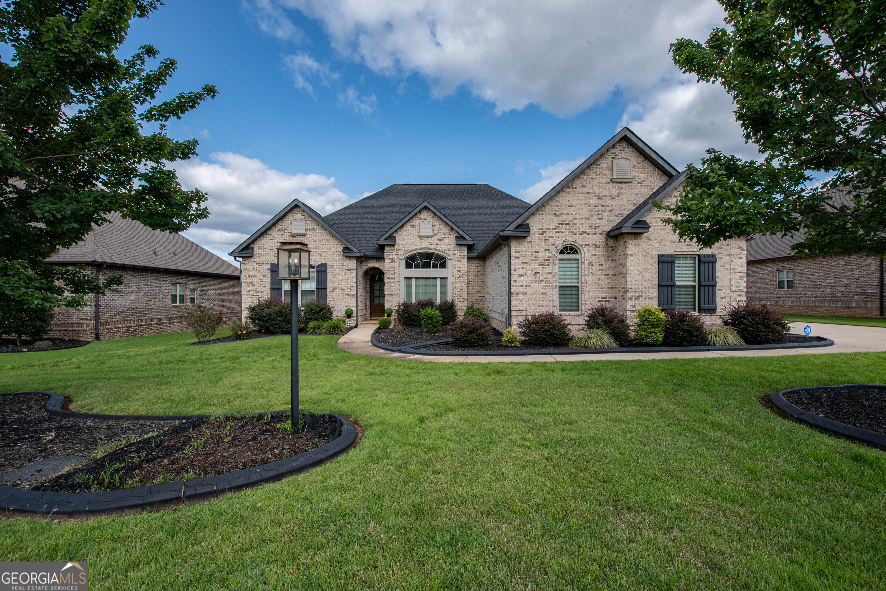 Welcome to 823 Kyler Ln, a stunning four-sided brick home located in the desirable McCarley Downs Subdivision. Built with quality and style in mind, this residence offers an exceptional blend of luxury and functionality-all just minutes from Robins AFB. Step into a spacious foyer with gleaming hardwood floors that flow into the expansive great room, complete with a cozy electric fireplace and soaring ceilings. The custom kitchen is a showstopper, featuring granite countertops, an oversized island with breakfast bar, stainless steel appliances, and designer cabinetry-perfect for everyday living and entertaining. Enjoy formal meals in the elegant dining room with coffered ceilings or casual breakfasts in the sunlit dining area. The split-bedroom layout provides privacy and comfort, with the luxurious owner's suite offering a retreat-like feel-complete with tray ceilings, a spa-style bath with double vanities, a jetted soaking tub, separate tiled shower, and a large walk-in closet. Additional bedrooms are generously sized, including one with its own full bath, ideal for guests or a private in-law suite. Step outside to the screened-in covered patio and fenced backyard-an ideal space for outdoor dining, morning coffee, or relaxing evenings. Other features include a side-entry garage, smart home technology, and energy-efficient construction. Conveniently located near top-rated schools, shopping, dining, and RAFB-this move-in ready home checks every box!
