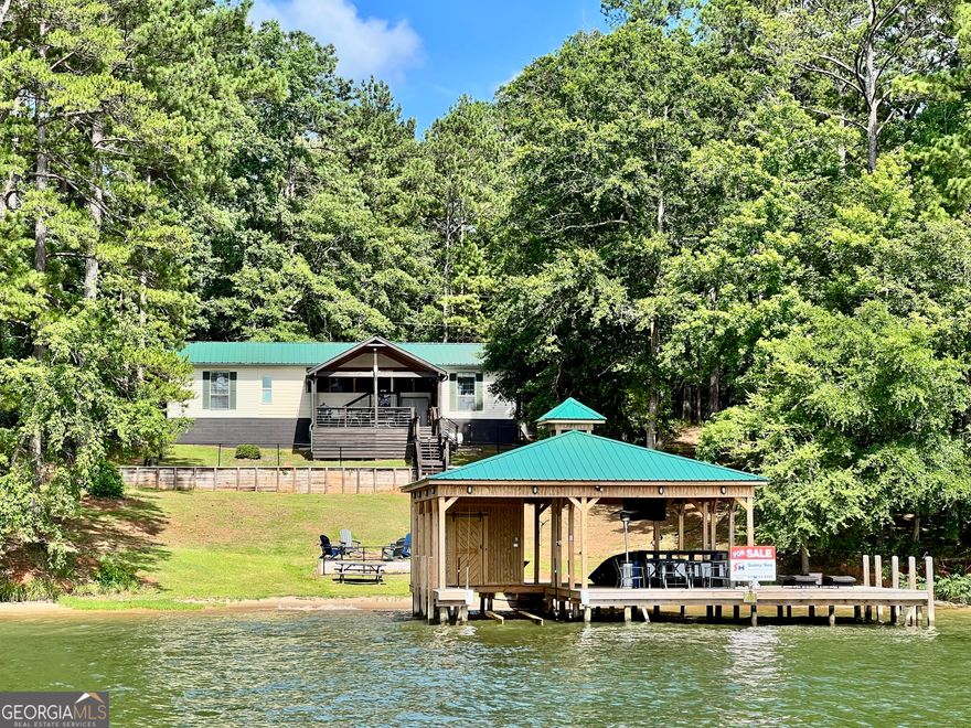 Fabulous big water view sitting in the middle of Lake Sinclair ! Enjoy stunning sunsets from your deck & dock ! This home features a brand new double slip dock with barn door storage, fresh water supply, and a large area perfect for gatherings and parties. Boasting 147 feet of beach shoreline, with no seawall to worry about, and water depths of 8 feet, it's ideal for water activities. The huge backyard invites outdoor fun, complemented by a tiered, screened-in, and covered porch - perfect for relaxing or entertaining. The fenced backyard provides privacy and security. Inside, the house features laminate flooring throughout, with three spacious bedrooms that can comfortably fit King-size beds - all offering breathtaking water views from your bedrooms. The open-concept kitchen seamlessly flows into the family room and breakfast area, creating a spacious and inviting living space. Additionally, there is a separate, large dining area with a small bar perfect for family gatherings and entertaining guests!