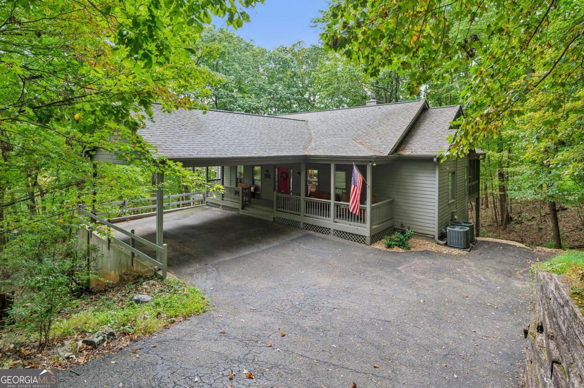 Nestled near the end of a serene Cul de sac, this beautiful mountain retreat overlooks a lush green -space forest that shifts from emerald to gold with the seasons. Floor to ceiling windows in the great room frame the ever-changing canopy, inviting natural light and wildlife into your daily life. The vaulted wood ceiling and stone fireplace capture the essence of rustic charm while offering modern comfort. This home's deck spans the rear facade, creating an ideal space for morning coffee or starlit dinners. You can hike directly from your driveway into miles of forested trails winding through Big Canoe's conserved green space. You will also be positioned in an amenity -rich mountain community with tennis courts, golf, clubhouse dinning, and lake access. The seller has invested significant time and money in completely renovating this beautiful 3-bedroom ,3 bath home. Complete living is all on one level, master bedroom,2 bathrooms, office/tv room, open kitchen, open dining room, sunroom with bay windows, den with stone fireplace, laundry room and a deck with a screened in porch. A large drive under carport takes you safely from your car to your front door regardless of the weather. The MAJOR upgrades include 1. Completely remodeled kitchen 2. A resent new roof and chimney 3. New heating/ air conditioning system for main and terrace levels.4. New terrace level hardwood flooring. 5. New hardwood stairs. 6. Wildlife exclusion package. 7 Chimney cleaned and sealed. 8 New master bedroom carpet. 9. Repainted main level. 10. Termite control package. The sellers have created a fabulous mountain home for the next owner. The pictures provided will show an incredible opportunity to feel the serenity and warmth of a Big Canoe Mountain home. Also, Hickory Trail is a quiet Cul de sac street wither you are walking or taking your dog out for a stroll. THIS is a must see at only $ 479,000. CALL TODAY. ALSO- Seller is willing to pay buyer the $4,500. Big Canoe initiation fee at closing.