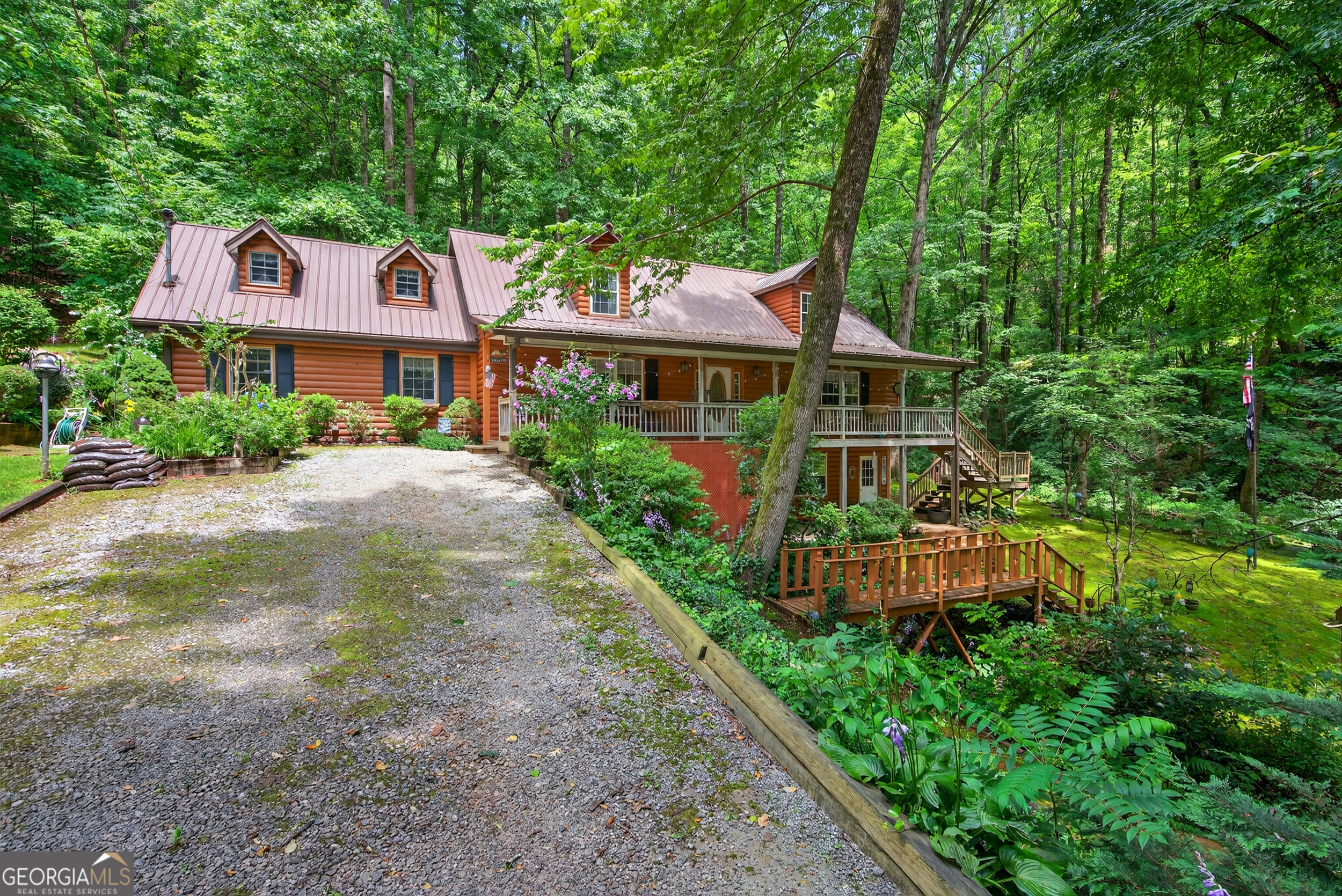 Peaceful mountain living awaits in this beautifully crafted furnished log home on Screamer Mountain, where three creeks merge on the mossy, lush oasis of a property. Step inside from the inviting covered front porch to an immaculate interior full of warmth and charm. The main level offers spacious living and dining areas, a cozy gas log fireplace, and a well-equipped kitchen with stainless steel appliances, ample cabinetry, pantry, and an island with breakfast bar. The primary suite features space for even the largest furnishings, a vanity area, and tub/shower combo. A laundry room, extra full and a half bath complete the main floor. Upstairs includes a large loft/living area and additional bedroom. The basement hosts a hobby/workshop space with workbenches and opens to a peaceful patio-perfect for entertaining or relaxing creekside. Just minutes from downtown Clayton and close to lakes and hiking, this home is being sold with an additional buildable lot with its own driveway.