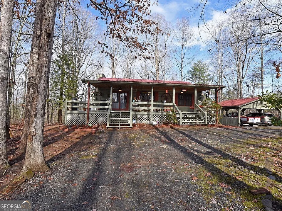 Rustic Mountain Retreat Just Minutes from Blue Ridge Attractions! Welcome to this cozy and spacious 3-bedroom, 2-bath cabin nestled in a prime location just minutes from Downtown Blue Ridge, the Toccoa River, Aska Adventure Area, and Lake Blue Ridge! With timeless tongue-and-groove woodwork throughout and a stunning natural wood-burning rock fireplace as the heart of the home, this rustic retreat blends classic charm with comfort. The main level features an open-concept family and dining area that's perfect for entertaining, with the kitchen tucked just off the dining space for easy flow and functionality. Two bedrooms and a full bath are located on the main level, while the lower level includes a third bedroom and full bath, plus a spacious flex area ideal for a game room, lounge, or future finished space to make it your own. A spiral staircase connects the levels, adding to the home's unique character. Outside, enjoy a 3/4 wrap-around porch with a screened-in section off the back perfect for taking in the peaceful surroundings. A circular driveway and carport provide ample parking, and the front yard already features a touch of landscaping. Whether you're looking for a full-time home, a weekend escape, or a fantastic short-term rental opportunity, this cabin has the potential and location to check all the boxes. Don't miss your chance to enjoy mountain living at its best!