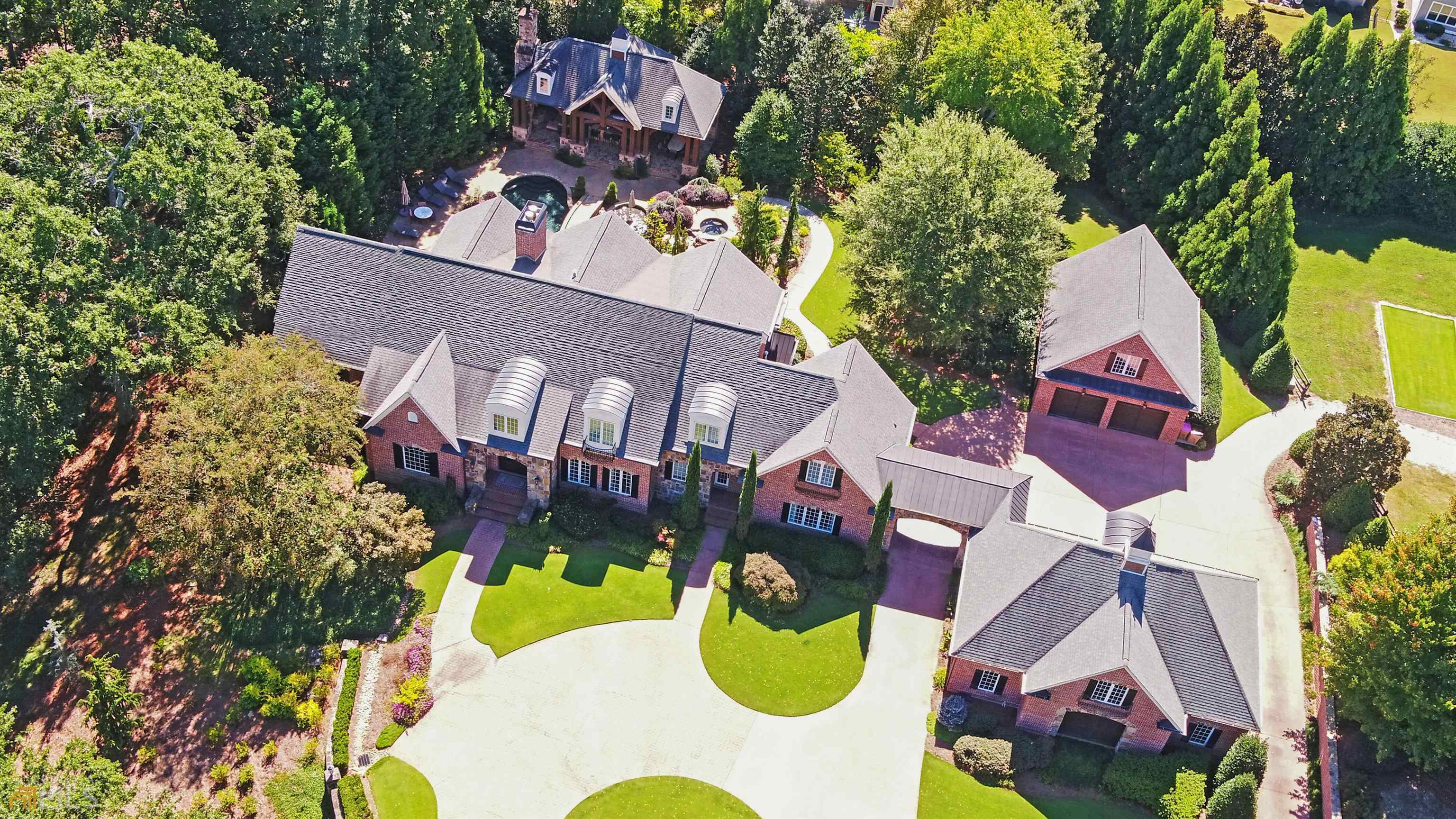 Imagine coming home to this extraordinary brick and stone custom estate with unparalleled privacy! Double iron gates welcome you into this well manicured 5.76 acre paradise. A circular drive and porte cochere lead to two garages with room for 5.5 vehicles along with a large parking pad. Both have finished, heated and cooled rooms above with one being an office and the other an exercise room. Amenities include a saltwater heated pool and spa, pool house with kitchen and fireside seating area, full bath and washer and dryer in the storage room. A deep well services the commercial irrigation system and the home has a whole house humidifier, dehumidifier and fresh air system. Double iron castle doors lead into the grand two story foyer flanked by the formal dining room on the right and a study / library on the left. Located on the main level, the primary suite offers a spacious spa like bath, an amazing spacious custom closet with a great view of your private pool paradise. The grand room with a floor to ceiling stacked stone fireplace accentuates the 24+ foot coffered ceiling with windows overlooking the amazing outdoor living space and pool. The well appointed chef’s kitchen with commercial grade appliances includes a Wolf gas cook top, Sub Zero refrigerator and freezer, Miele coffee bar, warming drawer, ice maker, dishwasher, vegetable sink, workstation and a large custom walk-in pantry. The upper level consists of three en suites all with custom walk-in closets and a bonus room with great storage space.Entering the terrace level you will walk into a game room with a large brick fireplace, bar area which has a Sub Zero fridge, wine cooler and wet sink, a wine cellar, half bath and gym. The theater room seats eight and the 130 inch screen and electronics will convey. On to the summer kitchen which opens to the dining area and family room. Everything you need for entertaining at the pool with another Sub Zero refrigerator, six burner gas cook top, warming drawer, microwave, dishwasher, ice maker and double sinks. A spacious bedroom with a full bath and custom walk-in closet completes the terrace level. As beautiful as the interior space is, you will also be amazed at the resort-like backyard featuring a covered lower patio, spa, salt water heated pool with water features and a bridge leading to the pool house. Great entertaining space with a stone fireplace and T.V. lounging area, a 60 inch grill, refrigerator, wet bar and a storage room which has a washer and dryer to conveniently wash your pool towels. The pool bath has a tile floor and shower. This majestic estate offers the best of both worlds as it is very private yet conveniently located close to area restaurants, the Northeast Georgia Medical Center/Hospital, Chateau Elan Winery and Resort and I-85. Call with questions or to schedule your private showing.