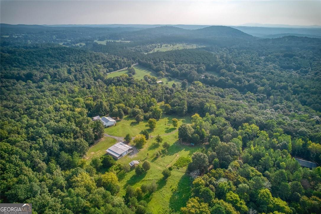 JUST re-listed with coveted additional acreage that has Tom's Creek running through it and approx 580 feet of road frontage on Mullinix Rd! This is an AMAZING opportunity for multiple home sites accessible from BOTH Connesena and Mullinix Rd - this home and 19.016 acres has a separate perpetual easement from Connesena Rd and a completely separate private gravel driveway with concrete, metal reinforced bridge all the way through the property down to an entrance on Mullinix Rd. Perfect for someone looking for land to build additional home/s for multi-generational living, rental income, an Airbnb and more. At the top of the acreage, you will find the custom 3 bed/2 bath farmhouse style Ranch home built in 2016, featuring exceptional craftsmanship from Hardie plank siding to a Galvalume metal roof, custom wood cabinetry to silent floor joists, rare granite counters and more. You will LOVE the stunning gourmet kitchen with a huge island for 6-8 people, a Master/Primary on the Main with a gorgeous master bath, a 2nd bedroom with it's own en-suite bath and clawfoot tub, a 3rd bedroom, a bonus room/den and a spacious mud room with laundry and walk in pantry, desk area & more. You will also love the step-less, single-level living with natural light and views from almost every room as well as mindful touches for accessibility throughout. Venture out the front door to find a huge enclosed front porch sun room - perfect for year-round relaxation or entertaining - and overlooking your own peaceful stretch of North Georgia countryside. To right of the home is an oversized 1500 SF lighted Metal Building or Workshop enclosed with a small room, loft, full bathroom with a shower and hot water, 2 sides shed off with approximately 1300 SF per side. Building and shed sides have concrete poured floors, several electrical outlets to run equipment or tools for woodworking or a shop and there is another small shed in pasture to park tractors or other equipment. The property is fenced in with exception of a small section from right side of the gate on Mullinix to right side of the bridge. Pasture and hardwoods include shagbark hickory, oaks, maples, cherry, cedar, dogwoods, etc. The orchard has pear and apple trees, one persimmon on property and fig bushes. Topping off this incredible property is the multiple home sites available as you drive down past the tree line toward Tom's Creek and Mullinix Rd. County water is already at house and available on Mullinix. A creek side home or cabin or two would be AMAZING here and have their own driveway and entrance. There are endless possibilities here for a family compound, income producing rentals, working farm, hobbies or work from home business needs. This peaceful property and land is a rare offering. Call for a private showing today!