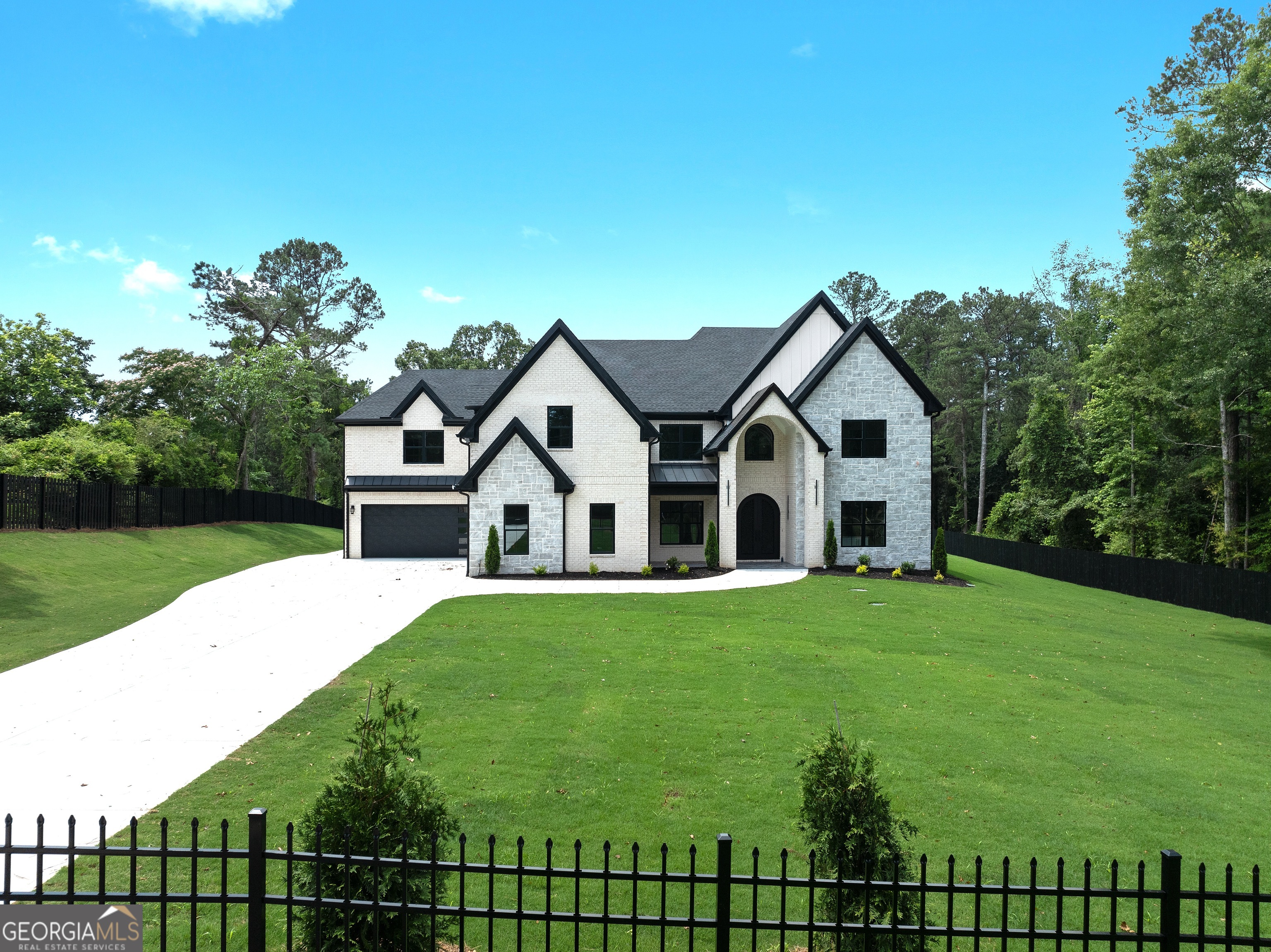 An extraordinary opportunity awaits to create your dream residence in one of Buford's most prestigious settings. Positioned on over an acre within the award-winning Buford City School District, this stately all-brick home blends timeless architectural elegance with the flexibility to tailor every detail to your lifestyle. Perfectly situated near fine dining, boutique shopping, and vibrant community amenities, the property represents the very essence of estate-style living. A privately gated drive leads to a commanding exterior adorned with brick, stone, and architectural metal roof accents. The expansive backyard, fully fenced and pool-ready, is perfectly positioned for resort-style outdoor living. Inside, a soaring foyer welcomes guests to a thoughtful floor plan designed for both grand entertaining and intimate family life. The Chef's Kitchen is a culinary masterpiece, showcasing a premium gas range with vent hood, an oversized quartz island, and a walk-in pantry with custom wall-to-wall shelving. Steps away, a second kitchen-ideal for catering, meal prep, or specialty cooking-offers functionality without sacrificing refinement. Luxury finishes are evident throughout, with a curated selection of designer options available and a full standard feature list provided upon request. The main-level Owner's Retreat serves as a private sanctuary, complete with triple picture windows framing serene backyard views. The spa-inspired bath features a freestanding soaking tub, frameless glass shower, dual custom vanities, and a boutique-style walk-in closet. Upstairs, four additional bedroom suites each include a private bath and spacious walk-in closet. A secondary laundry room enhances convenience for the upper level, while the vaulted media room, complete with fireplace, provides an inviting space for cozy movie nights or spirited game-day gatherings. The home's design also incorporates 10-foot ceilings on the main level, extensive millwork, custom cabinetry throughout, a four-car garage, and a covered veranda that seamlessly extends the living space outdoors. The unfinished terrace level offers endless potential for future expansion, whether envisioned as a home theater, gym, wine cellar, or additional living quarters. With luxury options throughout and the builder's willingness to accommodate custom design changes, this residence offers a rare chance to personalize every space to your exacting standards. Stock photography reflects the builder's previous work; finishes, floor plan, and specifications are subject to change at the builder's discretion. More than just a home, this is a statement of sophistication-crafted to inspire for generations.