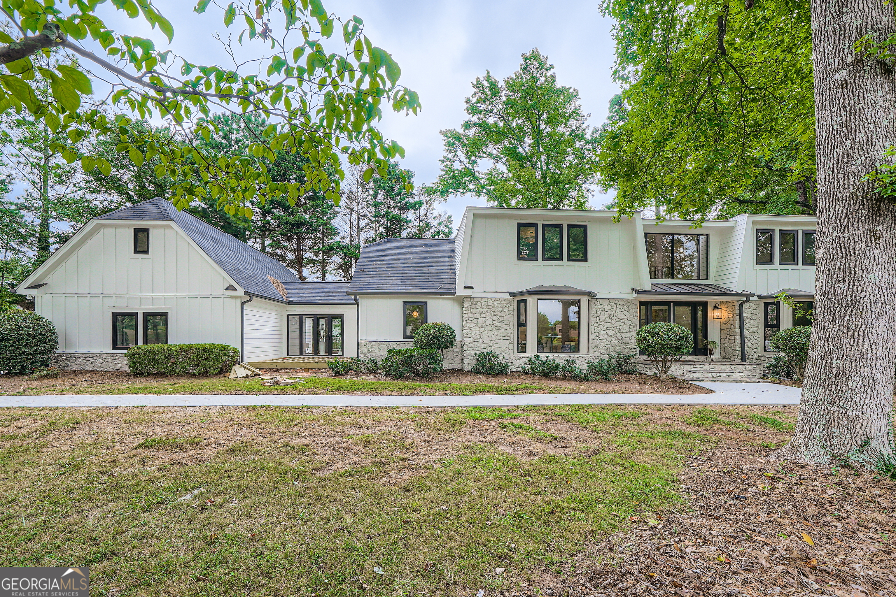 Welcome to 12890 Cogburn Road - a fully renovated estate with luxury finishes, privacy, and unmatched flexibility in the heart of Alpharetta! Set on 1.40 acres across from Cogburn Park and just minutes from Downtown Alpharetta, this no-HOA property offers the perfect combination of convenience, tranquility, and access to top-rated schools. Recent, full-scale renovations include a new roof, siding, soundproof windows, fresh paint, driveway, deck, garage doors, a chef's kitchen with custom cabinetry and granite island, designer lighting, and spa-quality bathrooms. The master bathroom features a recent professional restoration completed through insurance, with all work inspected and approved by the City of Alpharetta and a Certificate of Occupancy issued. Multiple living possibilities make this residence ideal for multi-generational living or income-producing rentals: * Main Home: 5,815 sq ft with 5 bedrooms, 4 baths, a grand 2-story foyer, formal dining for 12, spacious living areas with a masonry fireplace, and a main-level guest suite. The upstairs master retreat offers dual granite vanities, a custom walk-in closet, and an updated bath. * Lower Level: Fully finished with a media room, entertainment bar, and a complete 1-bedroom/1-bath in-law suite featuring its own living room, small kitchen, plus a loft bedroom and additional bath. * Detached Living: 744 sq ft, 2-bedroom/1-bath garage apartment with full kitchen, living room, and 2-car garage below. With four total garage spaces, including an oversized bay perfect for RV or boat parking, and a driveway that accommodates 10+ additional vehicles, the property is ideal for entertaining, housing multiple drivers, or storing recreational vehicles. Hop on a 5-minute E-Bike ride to enjoy all that Downtown Alpharetta has to offer. Just minutes to Avalon, Halcyon, GA 400, and highly sought-after Fulton County Schools.