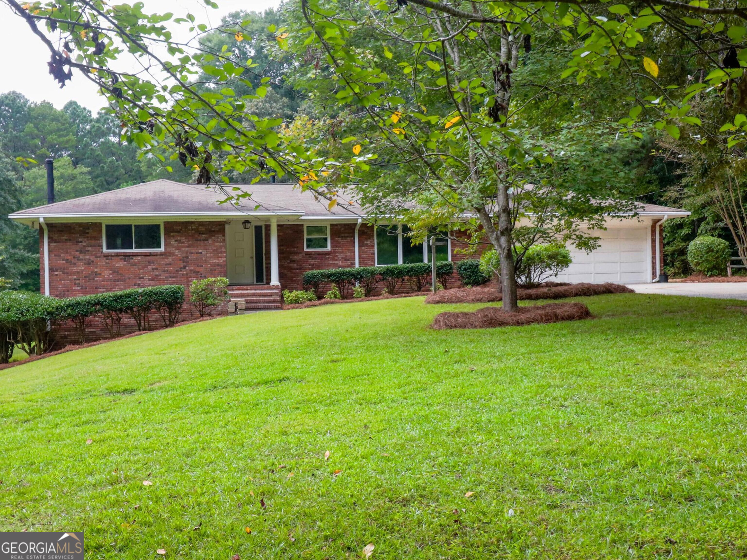 Welcome to 7800 Peters Road, a charming all-brick ranch nestled on a 3.7-acre wooded lot in the heart of Fairburn, Georgia. Built in 1972, this well-maintained home reflects timeless craftsmanship with thoughtful updates, offering both comfort and style. Inside, you'll find two spacious bedrooms and two full bathrooms, with luxury vinyl plank (LVP) hardwood floors in the bedrooms and that extend into the bright and inviting owner's suite. The heart of the home features a gorgeous kitchen and a warm masonry fireplace, perfect for gathering on cozy evenings. The attached two-car garage provides convenience and plenty of storage, while the full unfinished basement offers endless possibilities for future expansion, a a recreation space, or more. Outside, the private, wooded acreage gives you room to create the outdoor oasis you've always dreamed of-whether it's a garden, play area, or peaceful retreat. Despite the tranquility, the property is still close to schools, shopping, and local amenities, making it an ideal balance of seclusion and accessibility. With its classic four-sided brick design, expansive lot, and inviting interior, this home is ready for its next chapter. Don't miss your chance to make it yours.