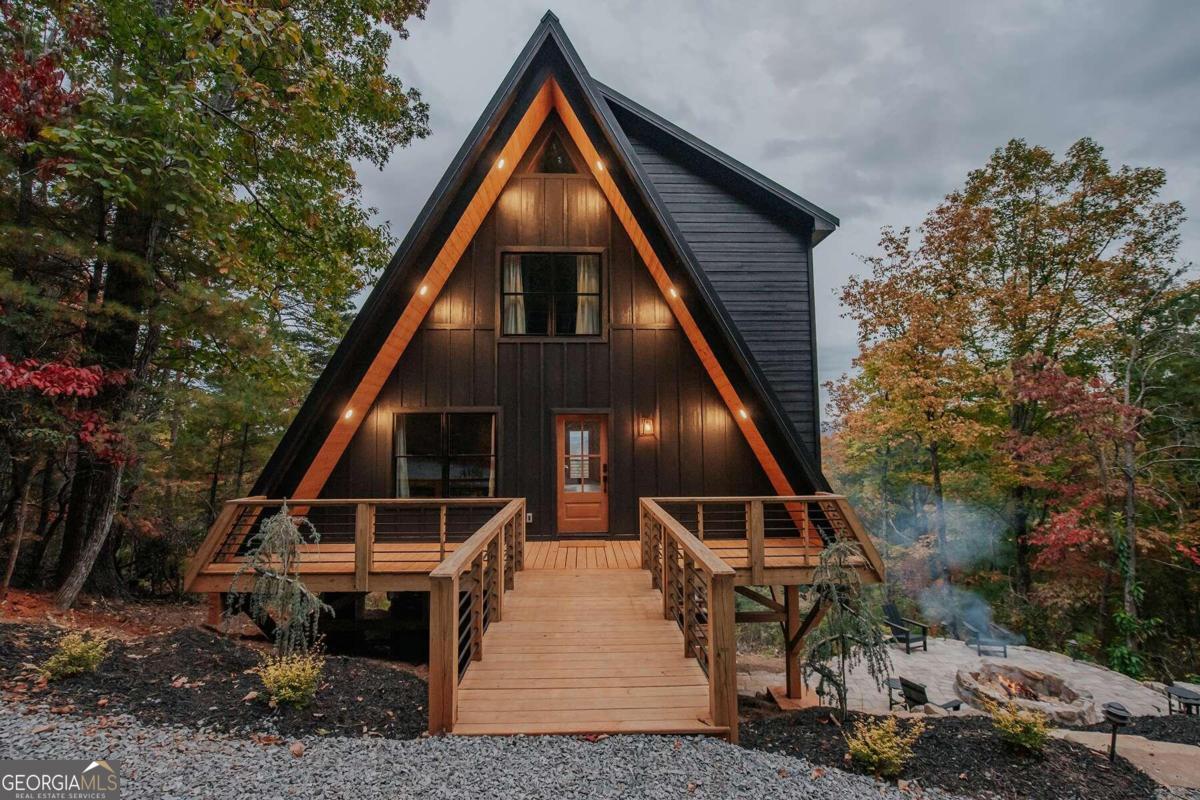 Discover the magic of this enchanting treehouse-style modern A-frame nestled in the breathtaking Blue Ridge Mountains. Surrounded by a tapestry of lush forest with the soft covering of turkeyfoot moss, this unique 2BR/2BA home offers 355+/- feet of tranquil creek frontage, where the soothing sounds of water harmonize with nature. Perched gracefully on a high landing, the home boasts spectacular views that unfold from the screened-in, covered back porch and the serene primary suite-your personal sanctuary amidst the treetops. Imagine sipping your morning coffee as the sun bathes the landscape in golden light. Step outside to a vast covered outdoor living space, perfectly designed for gathering and relaxation. Here, a cozy fire feature invites evening conversations under the stars, while a hot tub offers a warm retreat after a day of adventure. A winding path leads you down to the creek. This is more than a home; it's a serene escape into a world of natural beauty and tranquility.