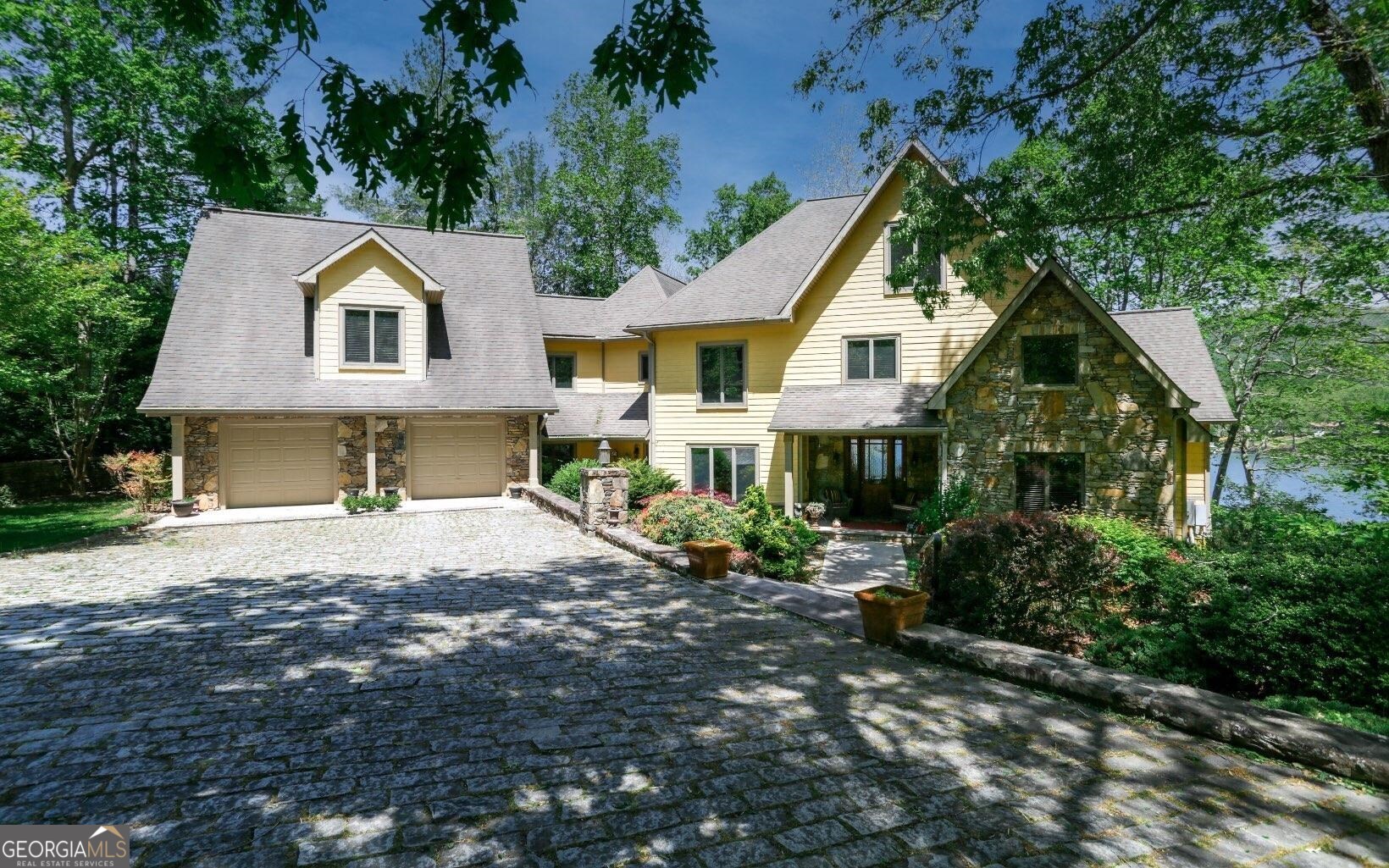 A magnificent Luxury Lodge Style Lakefront Home on the shores of beautiful Lake Chatuge! This professionally decorated 4-level home is situated on 3 spacious lots, offering an abundance of space & privacy. The stunning stonework & 6 fireplaces exude warmth & elegance throughout. Enjoy breathtaking lake & mountain views from every angle. Inside, you'll find heart of pine floors, a master suite on the main level, & a cozy library w/ a fireplace for those quiet moments of relaxation. 2 kitchens including a gourmet kitchen that boasts stainless steel appliances, perfect for culinary enthusiasts. 2 laundries. Unwind in the sauna or head outside to the double slip dock w/a party deck, ideal for entertaining friends & family. With a 2 car garage & an additional detached 3 car garage featuring an apartment above, there's ample room for vehicles and guests alike. Don't miss this opportunity to own a truly remarkable property that combines luxury living w/ the tranquility of lakefront living.