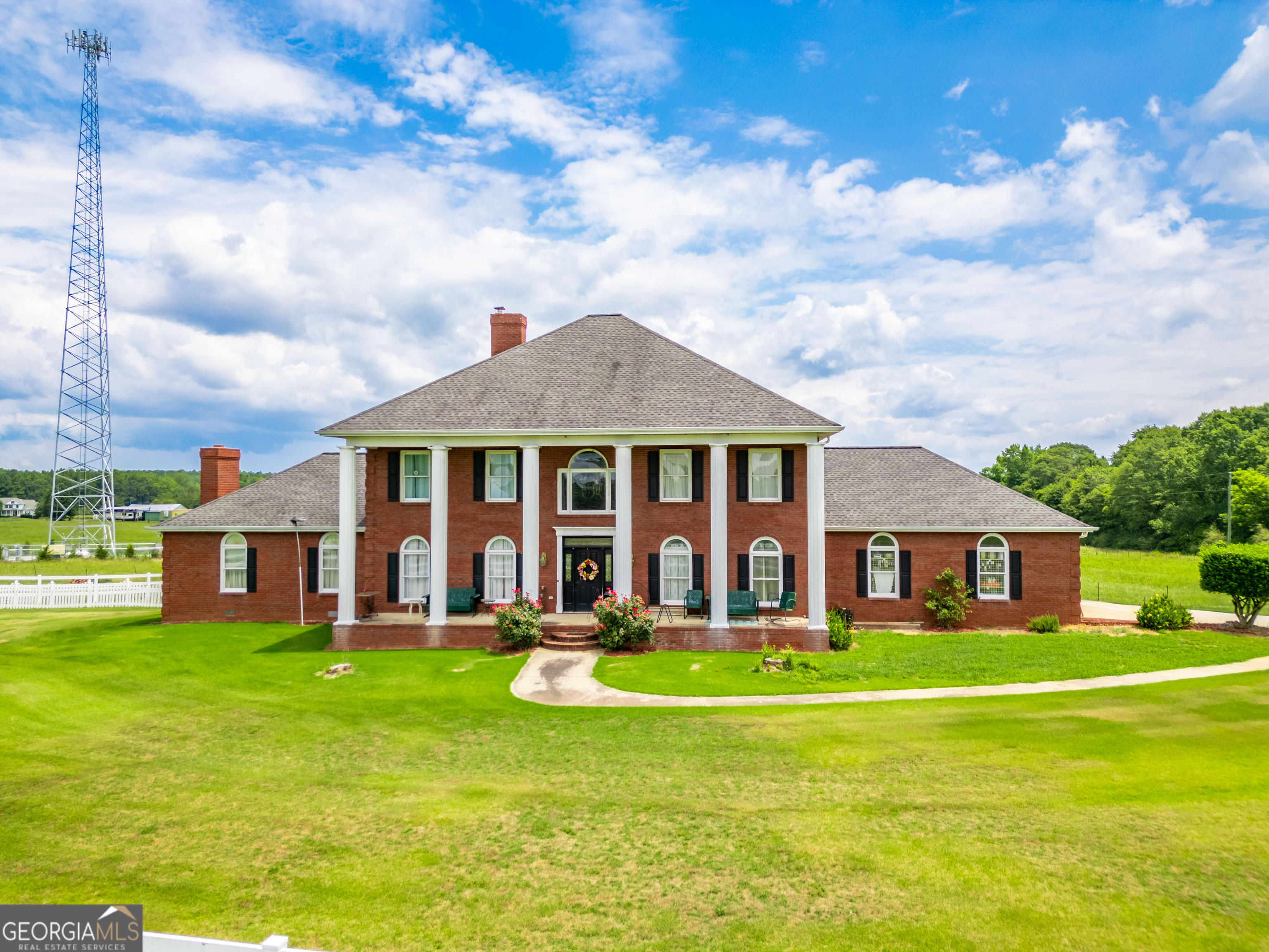 Country living at its best! This Estate Home is 4 side brick on 27+ acres with a nicely groomed level winding driveway located in the desirable community of Gratis, GA. Enjoy the winter months with 4 wood burning brick fireplaces, this home features a lodge style great room with a vaulted pine ceiling and floors made of australian cypress with brazilian inlay with a custom built lodge style bar providing an area for some really nice entertaining. There is a separate dining room and a country/farm style kitchen. An area of relaxation needed, well this home offers it with its screened in porch area with an attached large deck overlooking amazing scenery of level land, a beautiful pond, salt water swimming pool and sunrises to talk about. An extra large master suite with beautiful trey ceilings and brick fireplace offers desirable private space. The large master bath has a double vanity, jacuzzi tub, separate shower with steam features. Two additional bedrooms are oversized and has a spacious "Jack and Jill" bathroom which also has a double vanity. The property has many features being a 4 side brick pool house which offers great space including a bar area, full bathroom with steam features and a loft area. The property is fenced with vinyl and wire fencing, ready for any livestock on established pasture, there is a stocked pond on the property as well. You will find plenty of outdoor covered parking all around this property for golf cart(s), ATV's, Motorcycles, ect. On the property there is a metal barn with a bathroom and at this barn area more covered parking sized for RV parking and a walk in cooler (compressor is currently in need of repair). There is a cell tower on the property which brings in income and provides excellent signal for cell service. This property is located in a location that is convenient to Monroe, Loganville, Winder, Athens and Madison, GA. This home sits on its footprint in a perfect kind of way, its just a beautiful homeplace. Showings will need to be scheduled thru John Shea, Listing Agent.