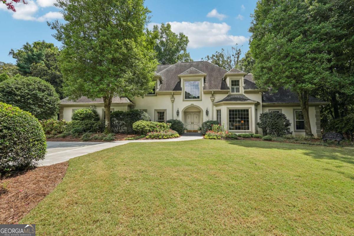 Resort-style living in the heart of Sandy Springs! This timeless European-style home is tucked away on a quiet cul-de-sac and offers 1.3 private acres with a heated saltwater pool, greenhouse, and turf side yard. A two-story foyer welcomes you into a bright, open layout. The updated kitchen features white cabinetry, quartz countertops, double ovens, two pantries, and a large island, opening to a sun filled keeping room. The vaulted family room boasts a brick fireplace, custom built-ins, and a chic beverage bar with storage and wine fridge. The main-level primary suite is a true retreat with its own fireplace, deck access, dual vanities, whirlpool tub, and steam shower. Formal living and dining rooms, a private home office, two half baths, and a spacious laundry room complete the main floor. Upstairs, generously sized bedrooms all have walk-in closets, while the finished basement offers a large rec room, fireplace, kitchenette, gym, bedroom, full bath, and a covered terrace overlooking the pool. Perfect for entertaining, the outdoor spaces feature a resort-style pool, expansive deck, and peaceful garden areas. Ideally located minutes from Chastain Park, The Battery, shopping, dining, hospitals, top schools, and major highways, this home blends space, privacy, and convenience in one of Sandy Springs most desirable locations.