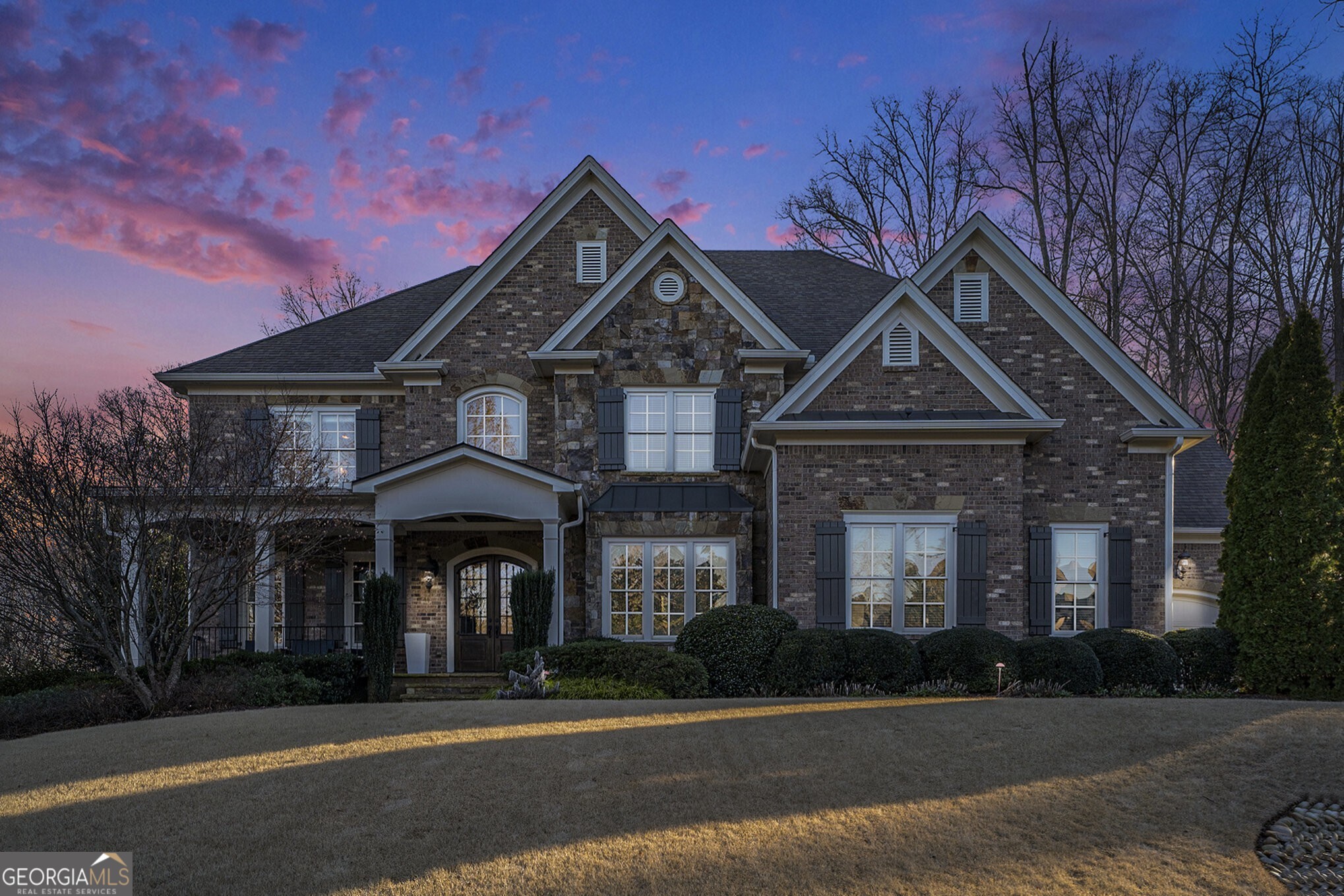 Welcome to 2885 Manor Bridge Drive, an exceptional 6-bedroom, 6-full bath, 2-half bath estate located in Milton's premier gated golf community, The Manor Golf & Country Club. Offering an unparalleled country club lifestyle, this home boasts elegant architectural details, high-end finishes, and resort-style amenities, making it an entertainer's dream and a private retreat. As you enter, you are greeted by custom solid wood front doors, leading into a light-filled foyer flanked by a study and formal dining room. The living room features a coffered ceiling, a stunning stone fireplace, built-in cabinetry, and French doors that open to a screened porch overlooking the private backyard oasis. The chef's kitchen is designed for both function and style, featuring an oversized island, built-in refrigerator, 48" professional gas range, walk-in pantry, and a butler's pantry with a beverage fridge and ice maker. The kitchen flows seamlessly into the vaulted keeping room, where exposed wood beams and a two-story stone fireplace create an inviting space for gatherings. A main-level guest suite with an en-suite bath and separate powder room offers comfort and privacy for visitors. The dream mudroom, with custom cabinets and cubbies, leads to the spacious three-car garage. Upstairs, the owner's suite is a true sanctuary, complete with a fireplace, sitting area, coffee/wet bar, and two custom walk-in closets. The spa-like primary bath boasts an oversized double vanity, a separate tub and shower, and a vaulted ceiling for an airy, luxurious feel. Three additional en-suite bedrooms and an expansive bonus room with built-ins complete the upper level. The fully finished terrace level elevates the home's entertainment offerings, featuring a state-of-the-art home theater, gym, full kitchen with two refrigerators, bar seating, a guest suite with a full bath, and an additional half bath. Outside, the professionally landscaped backyard is a private paradise, featuring a gunite pool, heated whirlpool spa, outdoor lounge area, and ample green space. Living in The Manor Golf & Country Club means access to world-class amenities, including a Tom Watson-designed golf course, a clubhouse, fitness center, resort-style pool, tennis courts, basketball, beach volleyball, playgrounds, and fine dining. With exquisite craftsmanship, luxurious updates, and a prime location in one of Milton's most sought-after communities, 2885 Manor Bridge Drive is a rare opportunity to own an extraordinary home that defines elegance, comfort, and prestige. Schedule your private tour today!