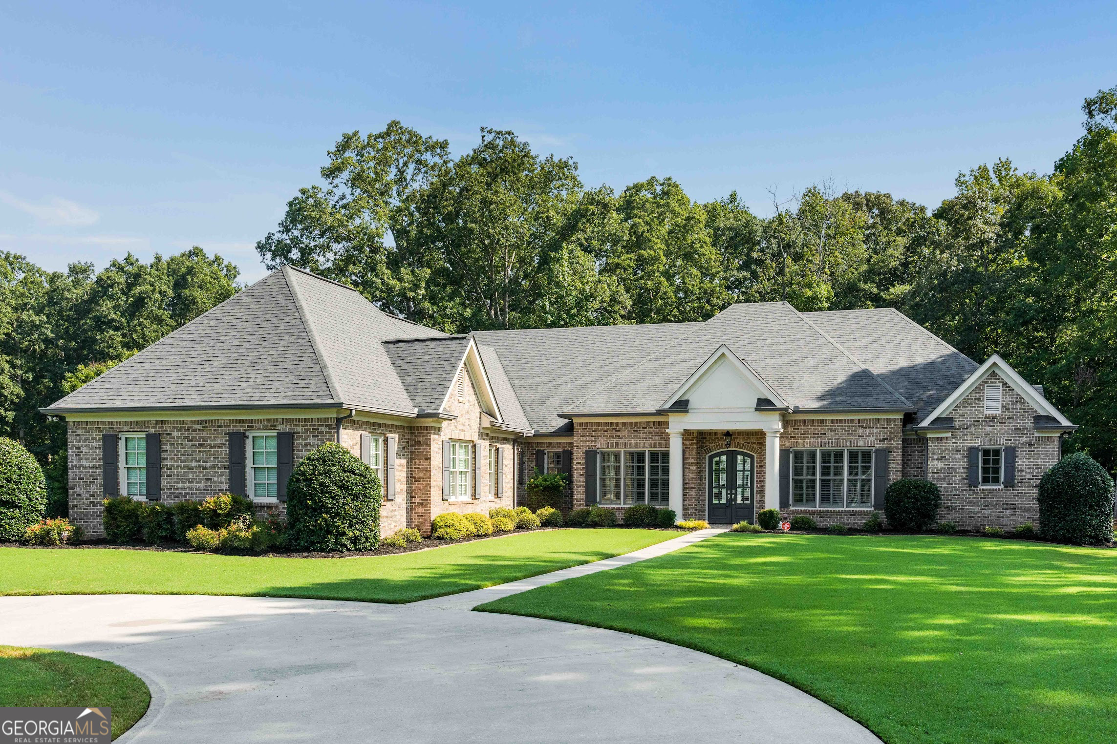 Welcome to 345 Sidney Lane - a single-story, custom-built, all-brick ranch where timeless craftsmanship meets relaxed coastal luxury. Set on a picturesque 1.36-acre corner lot in one of Fayetteville's most sought-after school districts, this 5,298 sq.ft. residence (3940 sq.ft. of living space, 1,000 sq. ft. of garage, and 300 sq.ft. of screened porch) offers open, airy living with meticulous attention to detail. At the heart of the home, the inviting great room showcases custom built-in bookshelves and a cozy fireplace, creating a warm and welcoming space perfect for relaxing with a book or gathering for a movie night. The great room opens seamlessly to an expansive screened-in porch with breathtaking wooded views - the perfect tranquil retreat. Just steps away, the chef's kitchen is designed for effortless entertaining, featuring a statement-making center island, an expansive breakfast bar, and a versatile dining area ideal for both everyday meals and casual gatherings. A keeping room provides a cozy spot to unwind alongside the kitchen, while the walk-in pantry ensures everything stays beautifully organized. Four spacious bedrooms each boast a private ensuite bath, offering comfort and privacy for family and guests. Throughout the home, custom cabinetry blends elegance with function, while sunlight floods the expansive living areas, highlighting the easy flow and sophisticated coastal-inspired finishes. An oversized, three-car garage with pristine epoxy flooring and custom, built in cabinets completes this exceptional home, providing ample space for vehicles, hobbies, and storage.