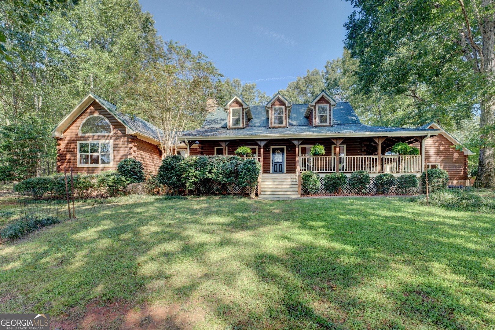Welcome to your dream escape, a stunning Craftsman log house nestled on an expansive almost 7-acre oasis that perfectly marries rustic charm with modern luxury. This remarkable property offers an unparalleled lifestyle surrounded by nature, privacy, and endless recreational opportunities. Drive through the gated entrance, and you are greeted by a fully-fenced paddock on the right and a breathtaking view of the lake and manicured lawns on the left. Follow the driveway lined with fuchsia and white crepe myrtle trees, cross over the picturesque bridge, and up the hill to arrive at the main dwelling with a gorgeous trellis meeting you by the attached wood paneled garage. This captivating home is enveloped by lush woods, and is fully fenced in providing an unparalleled sense of privacy and tranquility. Step out front to your fully-stocked lake (shared with only one neighbor), ideal for leisurely afternoons. The boat dock beckons you to launch your mini electric pontoon boat which conveys with the house. The lake is the perfect backdrop for your tranquil lifestyle. Relax and unwind in your inground saltwater pool, complete with cascading waterfall. The back deck, with its built-in benches and dedicated dining alcove complete with a gas grill, makes for the perfect setting to host summer barbecues and peaceful evenings under the stars. Accommodate family and friends in style with a charming detached guest house featuring a variety of amenities. Horse lovers will delight in the two large stables. The heated/air-conditioned shop/garage/barn offers endless possibilities for hobbies, storage, or even a creative workspace. The main house boasts a master suite with spectacular lake views, a cozy sitting area, a warm fireplace, and a walk-in closet. An additional fireplace in the living room provides ambiance on cooler evenings. Step onto the wraparound porch, complete with a swing and brand new ceiling fans, where you can sip your morning coffee or enjoy sunsets. The property also features a raised garden house, allowing you to cultivate your green thumb, a chicken coop, and an RV port. Explore the natural bounty of wild blackberries, muscadines, chanterelle mushrooms, and walnut trees that dot the landscape. Don't miss your chance to own this piece of paradise-schedule a tour today and step into the life you've always envisioned. Easy 1 hour drive from Atlanta and 40 mins to Athens.