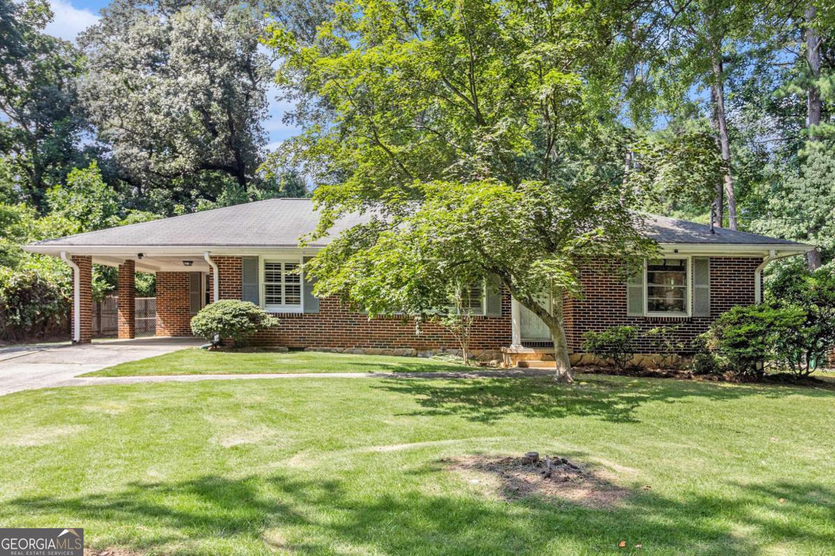 Welcome to your dream home overlooking paradise gardens! This beautifully appointed brick ranch boasts an inviting foyer and an open concept layout that seamlessly blends the kitchen, living room, and dining area. The heart of the home features a spacious kitchen with abundant counter space, stylish cabinetry, and a cork floor that adds warmth and character. Step into the 300 sq ft sunroom (not included in the listed square feet) where 2 sets of patio doors lead you to a stunning flagstone patio-perfect for entertaining or enjoying peaceful evenings. Adjacent to the patio, a covered deck overlooks a flat, private, and beautifully landscaped yard, ideal for gardening, games, or basking in tranquility. Inside, you'll find exquisite hardwood floors and energy-efficient double-pane windows throughout. Indulge in the spa-like full bath with its luxurious Creekstone shower floor and tile. Other features include: Separate laundry room, built in office, Plantation Shutters, & a 1 car carport* Need another bath someday? No problem...there is a huge hall storage room that could become the master bath (see floor plan). Deep plant and usable lot nestled in a quiet, central neighborhood location 3 blocks from Lindmoor Swim & Tennis. Amazing convenience to Emory, CDC, VA, CHOA, downtown Decatur, & Your Dekalb Farmers Market. Don't miss the chance to make this captivating property your own!