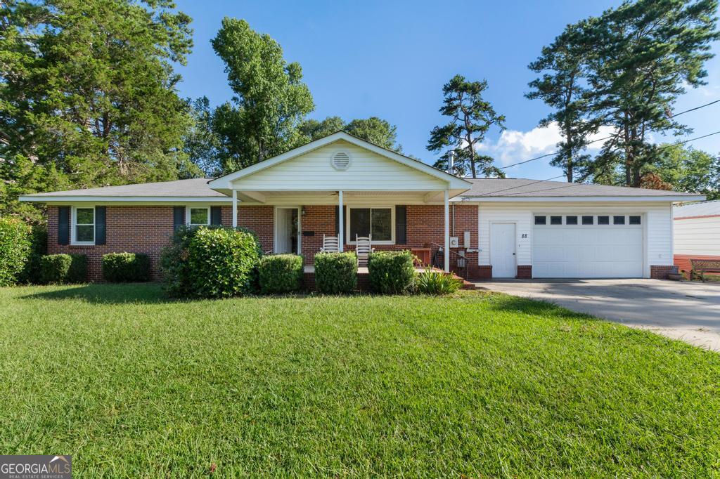 Summers not over yet. There's still time to settle into your new home -- right in the heart of downtown Locust Grove. These 3 bedrooms /1 bathrooms are move in ready!! Classic 1960 Brick RANCH has been beautifully remodeled and brought back to life...all the way down to the studs. Starting with all-new windows backed by a lifetime warranty and extending throughout the home with rich hardwood flooring and contemporary finishes. The chef's kitchen is a showstopper, featuring quartz countertops, soft-close cabinetry with under-cabinet lighting, a stainless steel farm sink, and iconic red Big Chill appliances. The tankless water heater ensures endless hot water, and a wood-burning stove adds cozy charm to the living space. Yes, it's one bathroom, but the spa-like bathroom includes a 20-inch rain showerhead and an enlarged wheelchair-accessible, tiled walk-in shower with sleek glass. Custom-made blinds and USB charging outlets in every room offer both convenience and style. Outdoor living is just as impressive. Enjoy evenings on your covered front porch or entertain on the oversized back deck reinforced for a hot tub, overlooking your large back yard. A custom-built woodshed with sliding barn doors, and a massive 20x30 metal building featuring a roll-up side door and built in shelving. Additional features include a full security system with cameras, built-in garage shelving, and a timeless design element that make this home one of a kind. Best of all? You're within walking distance to all that Locust Grove has to offer with shopping and dining. This small-town living with convenience, character, and an incredible price point.