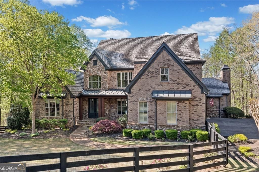 This private estate in Woodhaven Bend is on a charming almost 4-acre plot by the Etowah River. It's a unique find that combines nature with design. Beyond the gates, a winding drive leads to a custom-built home that showcases exceptional craftsmanship, comfort, and style, with rich millwork, six fireplaces, and coffered ceilings that evoke timeless elegance. The kitchen, recently renovated, is a warm and inviting space perfect for both casual gatherings and gourmet cooking. It offers leathered countertops, custom cabinets, and premium appliances. These details flow effortlessly into a warm fireside keeping room and a light-filled breakfast nook. The main-level Primary Retreat is a serene oasis, complete with a spa-inspired bath and spacious walk-in closet. Upstairs, three spacious ensuite bedrooms and a cozy loft provide ample space for guests or family. The terrace level is an entertainer's dream, featuring a media room, full bar, billiard space, a second spacious primary suite with an en suite bath perfect for guests or in-laws and a brand-new sleek home gym. Outside, your own private resort awaits, featuring an outdoor kitchen with wood-burning fireplace, stone patio for relaxing, a PebbleTec saltwater pool, cascading stone waterfall, hot tub, and direct access from your backyard to miles of scenic trails and the Etowah River. Woodhaven Bend residents enjoy exclusive access to community features. They can use a boat launch, relax in riverside pavilions, and explore 50 acres of preserved green space. This luxury retreat near Ball Ground offers privacy and convenience in a beautiful setting. Marketed exclusively by Path & Post Real Estate. Where we think every extraordinary home tells a unique story.