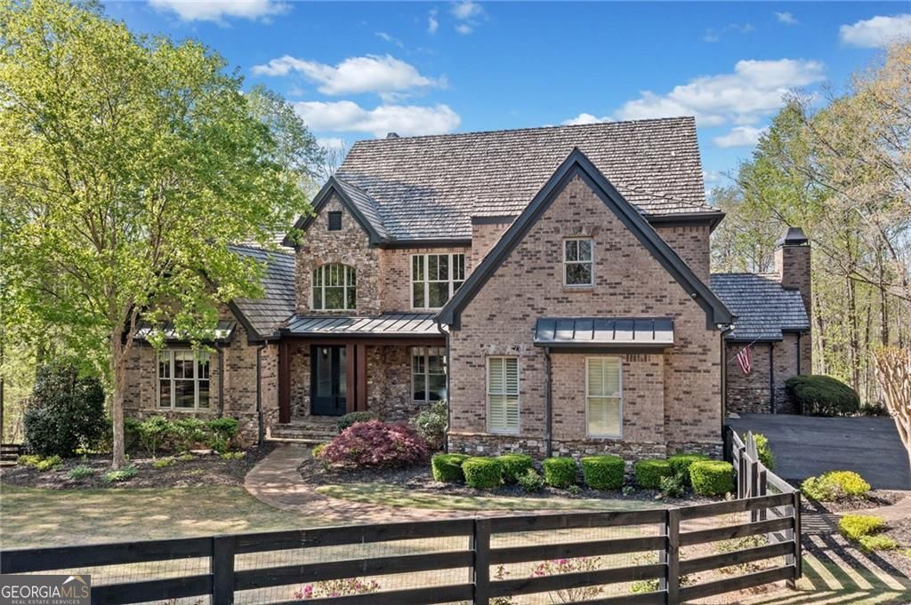 This private estate in Woodhaven Bend is on a charming almost 4-acre plot by the Etowah River. It's a unique find that combines nature with design. Beyond the gates, a winding drive leads to a custom-built home that showcases exceptional craftsmanship, comfort, and style, with rich millwork, six fireplaces, and coffered ceilings that evoke timeless elegance. The kitchen, recently renovated, is a warm and inviting space perfect for both casual gatherings and gourmet cooking. It offers leathered countertops, custom cabinets, and premium appliances. These details flow effortlessly into a warm fireside keeping room and a light-filled breakfast nook. The main-level Primary Retreat is a serene oasis, complete with a spa-inspired bath and spacious walk-in closet. Upstairs, three spacious ensuite bedrooms and a cozy loft provide ample space for guests or family. The terrace level is an entertainer's dream, featuring a media room, full bar, billiard space, a second spacious primary suite with an en suite bath perfect for guests or in-laws and a brand-new sleek home gym. Outside, your own private resort awaits, featuring an outdoor kitchen with wood-burning fireplace, stone patio for relaxing, a PebbleTec saltwater pool, cascading stone waterfall, hot tub, and direct access from your backyard to miles of scenic trails and the Etowah River. Woodhaven Bend residents enjoy exclusive access to community features. They can use a boat launch, relax in riverside pavilions, and explore 50 acres of preserved green space. This luxury retreat near Ball Ground offers privacy and convenience in a beautiful setting. Marketed exclusively by Path & Post Real Estate. Where we think every extraordinary home tells a unique story.