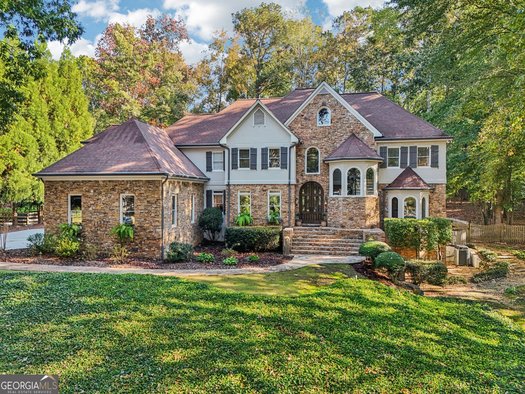Exquisite French Country estate designed by renowned architect Stephen Fuller-a masterpiece of timeless elegance and luxury living. From the grand two-story entryway with dual staircases to the richly detailed coffered and trey ceilings, hardwood floors, and intricate trim work, every inch of this home exudes sophistication. The updated kitchen is a chef's delight, featuring stainless steel appliances, granite countertops, a gas range, and a wall oven. The spacious kitchen and breakfast room flow seamlessly into a bright sunroom, perfect for relaxed mornings or entertaining. An oversized pantry with a second refrigerator provides exceptional storage and convenience. The primary suite with fireplace and a recently remodeled spa-like bath offers a serene retreat, while upstairs you'll find three additional bedrooms and two full bathrooms, providing ample space for family or guests. The finished terrace level is an entertainer's dream, complete with a pub-style bar, theater room, guest suite, and full bath. Enjoy the warmth and ambiance of four fireplaces throughout the home, each adding charm and comfort to the living spaces. Step outside to the private, professionally landscaped backyard surrounded by evergreens and featuring flagstone walkways, a sparkling pool, and a relaxing spa-your personal oasis. Located in the sought-after Polo Golf and Country Club, within walking distance to Vickery Village, and just minutes from Cumming City Center, Halcyon, Big Creek Greenway, top-rated schools, and premier shopping and dining. With luxurious finishes and exceptional craftsmanship throughout, this residence offers both grandeur and warmth in one perfect package.