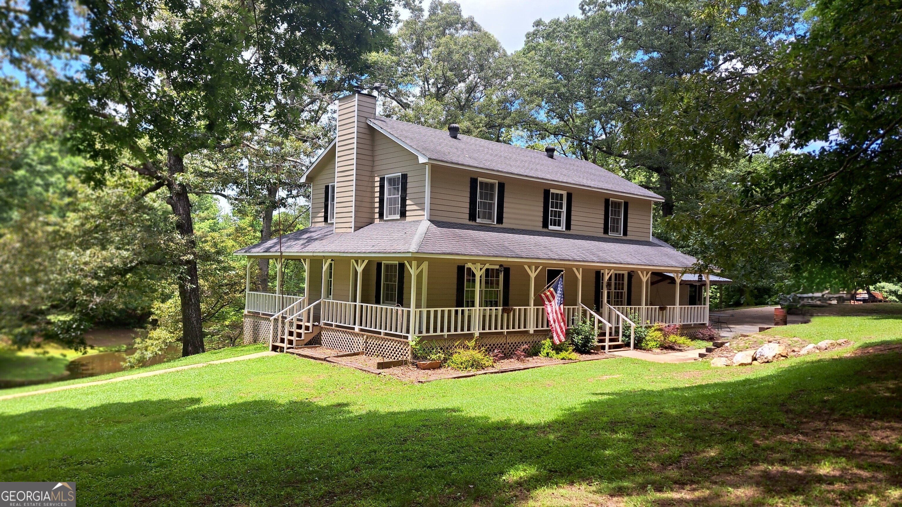 Welcome to a peaceful country retreat on 11.21 acres of natural beauty and rustic charm. Tucked away in a quiet rural community, this property offers space to roam, a slower pace, and the kind of setting that makes you want to stay awhile. The home features a classic country design, complete with a wraparound porch that invites you to relax and enjoy the surrounding landscape. Whether you're sipping coffee in a rocking chair or watching the sun set over the trees, it's the perfect place to unwind. On the side of the home, an inground pool offers a private spot to cool off in the summer or host gatherings with friends and family. Out back, a serene, stocked lake adds to the property's appeal-ideal for fishing or simply enjoying the peaceful, natural surroundings. There's also a barn with a loft and a separate equipment shop, providing plenty of space for storage, hobbies, or animals. Inside, the home features wood columns, hardwood floors, and a cozy wood-burning stove that add warmth and rustic character. Natural light pours in through the windows, and every room reflects the comfort and simplicity of life in the country. Tucked away in the quiet of the countryside, this property offers the kind of privacy and space that's hard to find-yet still within reach of nearby towns when needed. Whether you're looking for a weekend getaway, a full-time homestead, or a place to put down roots, this one offers the land, the charm, and the potential to make it your own. Come explore everything this special property has to offer.