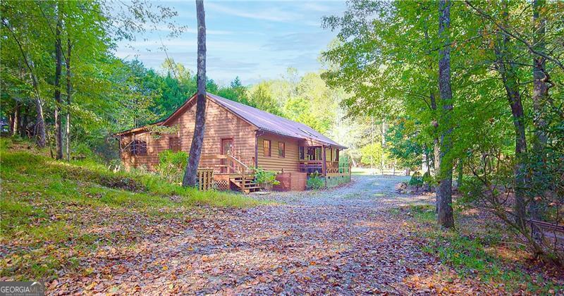 Welcome to your dream mountain retreat! Nestled in the picturesque mountains along Vandegriff Creek in Elijay, GA, this enchanting ranch cottage offers a harmonious blend of natural beauty and modern luxury. *Spanning 3.52 acres, with over 350 feet of pristine creek frontage, this home is a rare sanctuary for those seeking tranquility and refined living. *Step inside to vaulted ceilings with skylights that flood the space with natural light. Scenic views surround you from every window, while warm hardwood floors and tastefully updated lighting and hardware add a touch of sophistication. The open-concept floor plan creates an inviting space for entertaining and making memories with loved ones. *The heart of the home, the kitchen, boasts striking black granite countertops with elegant white veining, complemented by glossy ceramic backsplash tiles. Sage green cabinetry and a beautifully crafted wood island complete the space, creating both style and function. Just behind the kitchen, you'll find convenient access to the laundry room, mudroom, and additional storage. *Anchoring the living area is a character-rich black stove pipe on a stone threshold, providing both warmth and a focal point. The open game room, with its peaceful views, offers flexible use as an office or additional lounge area. From here, step out onto the expansive back deck that overlooks the property, leading to a stone patio that provides a pathway to the yard and a large firepit, perfect for gatherings under the stars. *In the owner's suite, large windows flood the room with sunlight and offer serene views of the creek and the firepit, creating a perfect sanctuary to start each day. *Outdoors, relax around the custom-built firepit, designed to seat eight comfortably, with breathtaking views of the neighboring horse pasture and the soothing sounds of the babbling creek. *For nature lovers and adventure seekers, a scenic hiking trail into the mountains lies less than half a mile away. The Chattahoochee National Forest and the Blue Ridge Wildlife Management Area are just beyond, offering countless trails, waterfalls, and outdoor attractions. Sold fully furnished, this property offers turnkey luxury with exceptional short-term rental potential. Just 25 minutes from Downtown Ellijay, with its charming orchards, wineries, shopping, and dining, this mountain oasis offers the perfect balance of seclusion and convenience. *Whether you're seeking a personal retreat or a lucrative investment, this mountain cabin exceeds every expectation. The HOA is comprised of 3 homes only. No Fees. Minimal restrictions. Road has been recently paved!