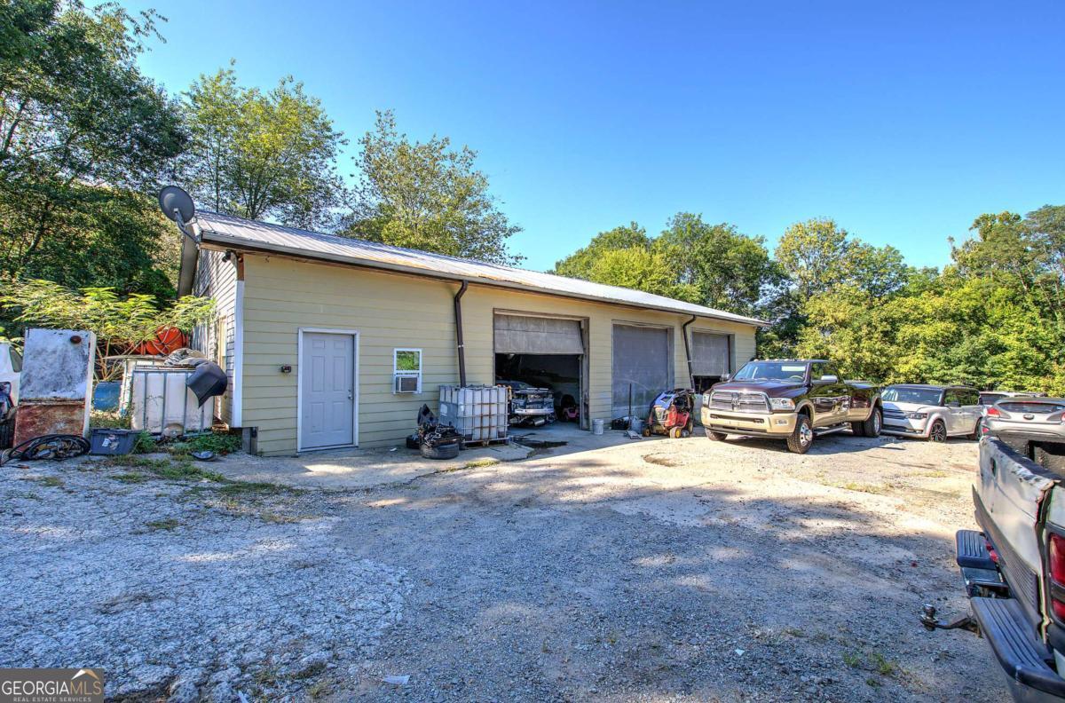 Looking for the perfect location to grow your business? This versatile 2,600 sq. ft. building offers endless potential for a wide range of commercial uses. Currently operating as an autobody shop, the property features a spacious open layout, low-maintenance vinyl siding, a durable metal roof, and three oversized garage doors for convenient access. Inside, you'll find electricity in place along with a welcoming reception area, ideal for meeting clients or customers. The property sits on a securely fenced .350 acre lot, with paved frontage that's perfect for parking or outdoor workspace, plus a grassy rear section for added flexibility. Zoned R-3 residential but taxed as Universal - Commercial (NEC), it provides a rare opportunity for multiple future uses. Its prime location, just minutes from I-75, the Booth Western Art Museum, the Tellus Science Museum, and the Savoy Automobile Museum, makes this property not only practical but also an excellent investment opportunity.