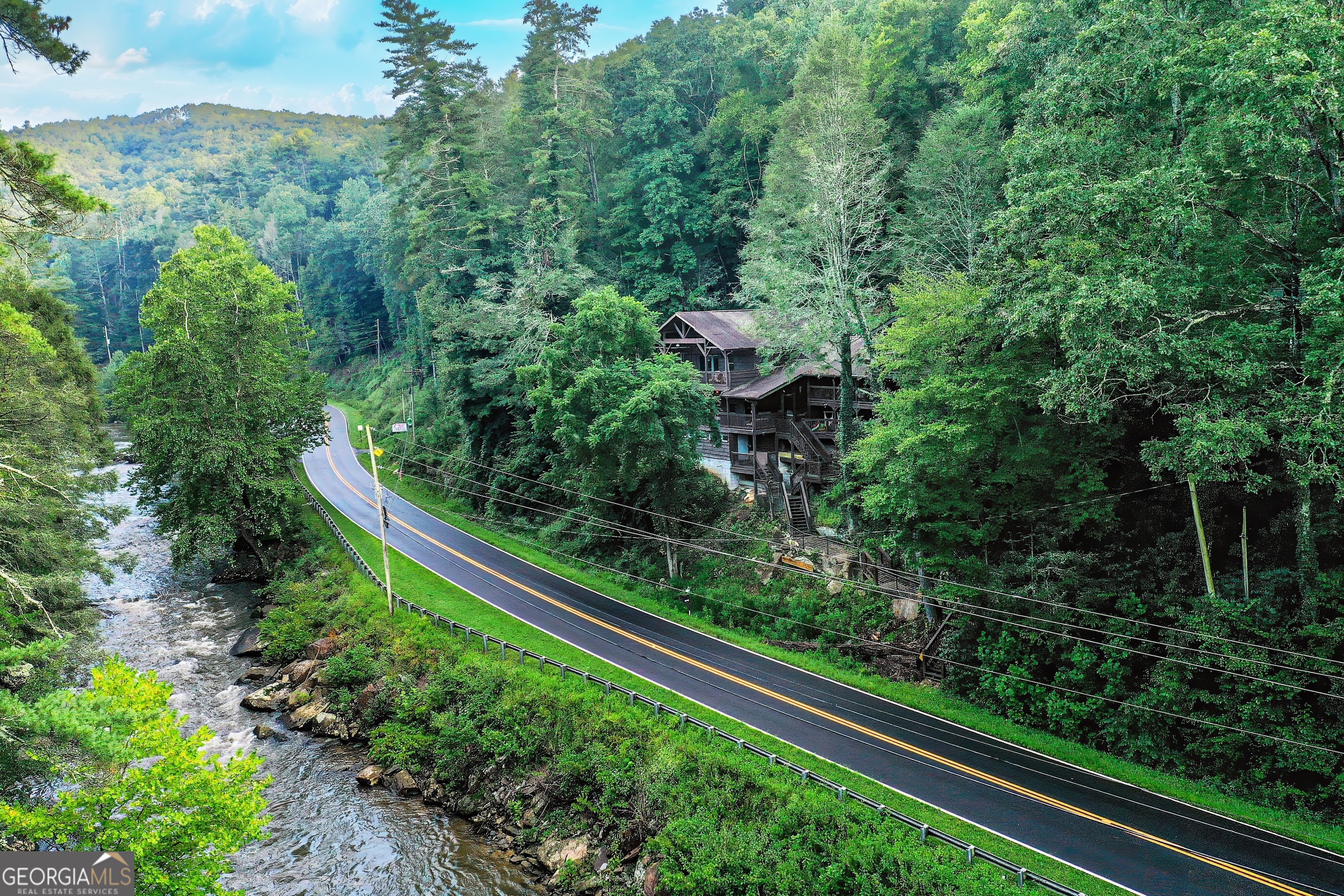 Experience one of the most distinctive riverfront homes in the North Georgia Mountains. Sitting along the roaring Toccoa River in the heart of the Aska Adventure Area, this one-of-a-kind 3BR / 5BA cabin comes fully furnished, spans 3,076 sf, and sleeps up to 14 guests. Built in 1987 and meticulously maintained, it blends rustic Appalachian charm with modern comforts, making it ideal as a family retreat or a proven short-term rental investment. The home offers two en-suite bedrooms with king-size beds and balconies overlooking the river, plus a guesthouse suite with a king bed, balcony, kitchen, bath, and a two-person hot tub. A honeymoon suite includes another balcony and a jacuzzi with spectacular river views. To maximize accommodations, the home also features four private loft-style "caves" with low ceilings, each accessed by a short flight of stairs and cooled and heated with an HVAC vent. These cozy, unique spaces include three queen beds and one twin each, making them a favorite for families and groups. There are multiple living areas, a large kitchen and dining room with seating for 14, plus a kitchenette in one suite. Outside, expansive decks showcase the sights and sounds of the rushing Toccoa, while a five-person hot tub and outdoor gathering areas create the perfect backdrop for relaxation and memory-making. For outdoor enthusiasts, the property offers direct unrestricted river access for fishing just across the street. From parking lots 1 and 2, you can walk down the driveway to Stanley Rapids, a historic public site where you can kayak, tube, fish, sunbathe, or capture unforgettable photos. All of this comes with the benefit of a prime location, located just minutes from downtown Blue Ridge, the Toccoa Riverside Restaurant, and miles of scenic hiking trails. Whether you're looking for a full-time residence, a luxury mountain getaway, or a turn-key rental with excellent income potential, this property is a rare riverfront gem that truly has it all.