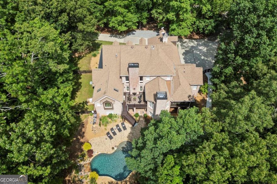 Welcome to Bent Tree Estate, an elegant and private retreat set on nearly 8.5 acres in a quiet gated enclave-where luxury, comfort, and nature come together in perfect balance. This four-sided brick estate includes a stunning main residence with over 8,900 sq. ft. of refined living space and a separate 1,000+ sq. ft. guest house, ideal for extended family, guests, or rental income. Designed for both grand entertaining and everyday ease, the main home offers 6 bedrooms, 5 full and 2 half baths, and three finished levels of thoughtfully designed spaces. The main level features a spacious primary suite with a spa-inspired bath and dual walk-in closets, a welcoming guest suite, and a beautifully renovated chef's kitchen with premium appliances, custom cabinetry, and a large island for gathering. Throughout the home, five fireplaces, rich hardwood floors, and custom finishes create warmth and timeless appeal. Upstairs, three well-sized bedrooms include an en-suite and Jack-and-Jill bath, while the terrace level offers the ultimate leisure retreat-complete with game room, kitchenette, sauna, full bedroom suite, and direct access to the heated Pebble Tec saltwater pool. Enjoy year-round outdoor living with a wraparound front porch, screened porch, and patio overlooking the pool and wooded backdrop-perfect for peaceful mornings or lively gatherings. Additional highlights include a whole-house generator, detached two-car garage with EV charging station and loft storage, plus a total of five garage spaces between both homes. The guest house currently generates $1,575/month in rental income through February 2026, offering built-in value and flexibility. Tucked along a private, tree-lined road shared with a handful of neighbors, Bent Tree Estate provides the rare combination of serenity and convenience-just minutes from GA-400 and the North Georgia Premium Outlets. Experience the best of North Georgia living in a setting that feels worlds away.