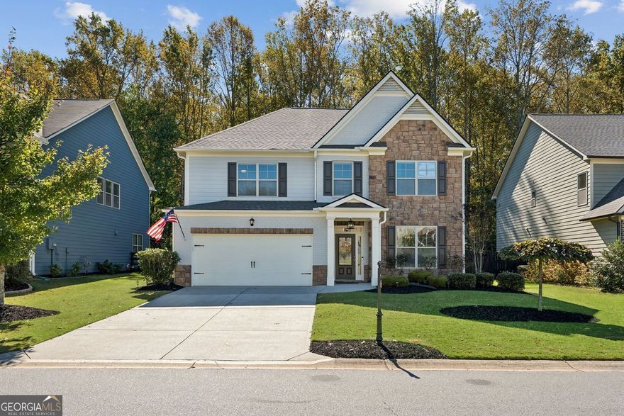Fabulous Like-New Home in Sought-After North Forsyth Swim/Tennis Community! This well-maintained home offers a bedroom and full bath on the main level, along with beautiful 5" hardwood floors throughout. The separate dining room features coffered ceilings, and the gourmet kitchen includes a large island with seating for four, granite countertops, stainless steel appliances, a 5-burner cooktop, double ovens, a tiled backsplash, an oversized butler's pantry, recessed lighting, and tall cabinets. The bright breakfast area opens to a spacious family room with a gas-log fireplace. A mudroom completes the main floor. Upstairs, hardwood stairs lead to a large loft currently used as a media room. The primary suite includes a tray ceiling, sitting area, and a tiled bath with separate vanities, a soaking tub, tiled shower, and a huge walk-in closet that connects to the laundry room. The secondary bedrooms are generous in size and share a full bath with a double vanity and granite countertops. Enjoy the private, wooded, fenced backyard with a covered porch featuring a vaulted ceiling-perfect for relaxing or entertaining. Conveniently located minutes from the GA Premium Outlet Mall, dining, and Lake Lanier. Community amenities include two pools, a clubhouse, playground, tennis courts, and a scenic lake. Located in highly rated Forsyth County schools.