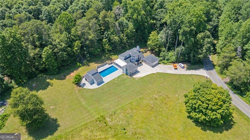 One-of-a-Kind Mini Estate on 3.7 Acres! Ready to trade cookie-cutter for character? Welcome to 6592 Rufus Bryant Road-a playful contemporary hideaway with endless potential and personality-PLUS! Tucked down a peaceful country road, this sprawling 3-bedroom, 2.5-bathroom fixer-upper also comes with a 1-bedroom, 1 bathroom detached GUEST HOUSE! Perfect for hosting family, setting up your art or yoga studio, or turning into a short-term rental for instant income potential. The guest house adds incredible versatility and value. Just minutes from charming downtown Dahlonega, Lake Lanier, Gainesville, and all the mountain adventures your weekend bucket list can handle, this property is a hidden gem begging for your personal touch. Step inside the expansive home and let your imagination run wild. Vaulted ceilings and tons of natural light offer an airy canvas, ready to be transformed. The family room is anchored by a cozy fireplace-one of three in this unique home. Imagine chilly evenings curled up by the fire, planning your next home improvement adventure. Love hosting big gatherings? You'll be thrilled by the oversized dining area, flowing effortlessly into a huge bonus room with yet another fireplace-perfect as a main-level owner's suite, epic game room, or creative studio. But wait, there's more: climb the spiral staircase (yes, really!) up to your whimsical lookout loft. Whether it's a reading nook, a stargazing observatory, or the ultimate secret fort, this loft promises quirky charm and endless inspiration. Outside, your very own private resort awaits. Splash into summer fun immediately-the massive in-ground pool features a brand-new liner, meaning pool parties, BBQs, and lazy Sundays lounging with friends start NOW. With 3.7 acres of flat, usable land zoned Agricultural, your dreams of homesteading, gardening, or even keeping horses and goats can come true. Parking your RV, boat, or fleet of ATVs? Absolutely no problem here-there's room for everything and no HOA to slow you down. Priced attractively and sold as-is, this one-of-a-kind property invites you to bring your tool belt, your Pinterest inspiration boards, and your sense of adventure. It's quirky, it's cool, and it's ready to become your masterpiece. Ready to write the next amazing chapter at 6592 Rufus Bryant Road? Your dream project awaits-just bring your swimsuit and imagination!