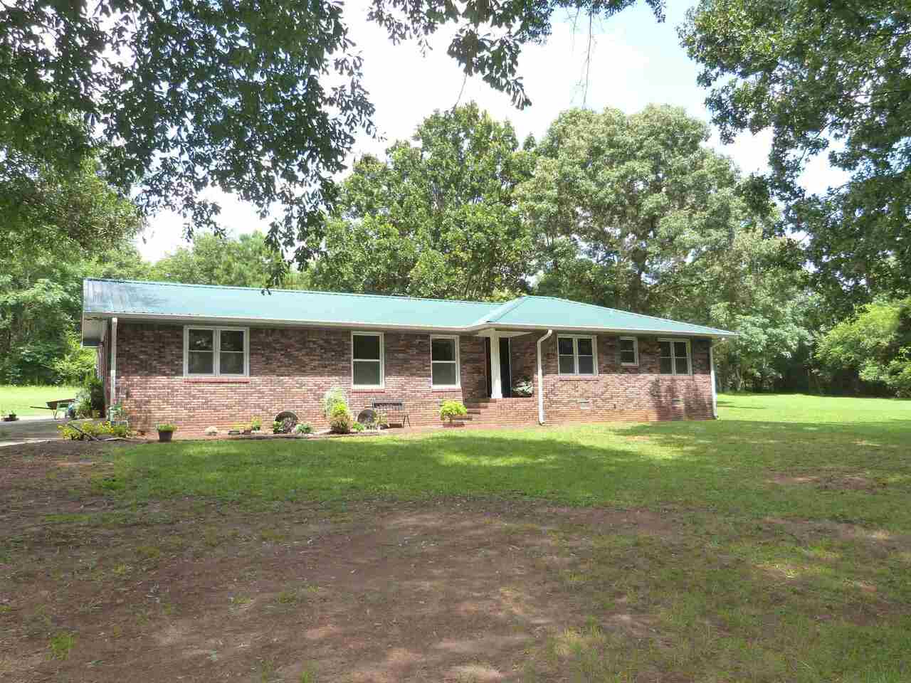 Nice 4 board wooden fence along the road with gated entrance. This beautiful property has 3.3+ acres wooded and open with Large 4-sided Brick Ranch with lots of potential just needs some TLC. Wood Floors in Bedrooms & Dining Room. Large Kitchen has lots of cabinets, Smooth-top Range, Refrigerator and Breakfast Bar. Breakfast Area has Masonry Fireplace. Large Laundry/Mud Room is plumbed for utility sink and has great views of back yard. Oversized Great Room w/ lots of windows. Master has Newer Tile Shower. Hall Bath has double Vanities and tub/shower combo. 3rd Bedroom has a built-in sink too. Big 2-Car Carport. New Survey in 2020. No HOA. Metal Roof 6yrs old. Most of the windows have been recently replaced. Septic located in Front/side Yard. Well located in back. No County Water available. 577 +/- feet of road frontage.