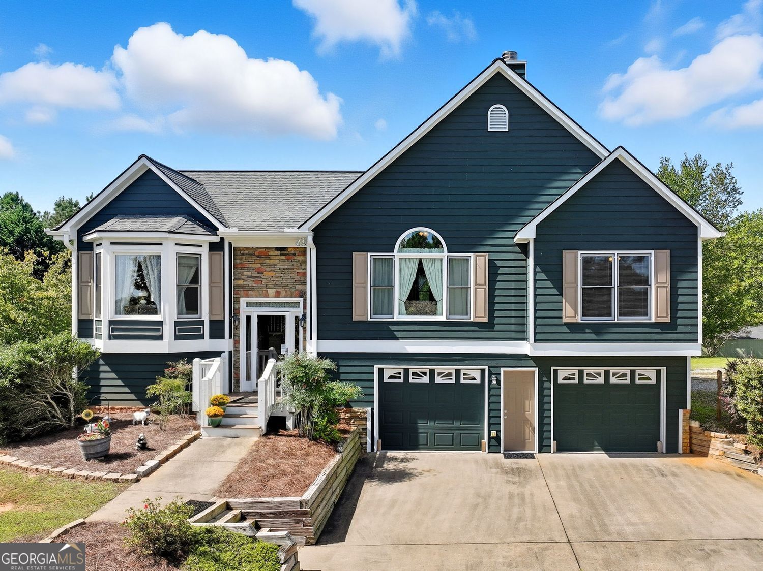 Set on a full acre with no HOA, this is a move-in ready home with a finished terrace level with private entry, and a backyard built for both work and play. From the curb, the dark Hardie Plank siding, stone accents, and crisp white trim create timeless appeal and inside, vaulted ceilings and floors make the main living space feel bright and open. Whether you're hosting, gardening, or need room for extended guests, this home is built to flex with your life. The main floor features an inviting living room with a stone fireplace and large arched window that fills the space with natural light. The adjoining kitchen includes solid wood cabinets, white appliances, and a double sink beneath a sunny window. A nearby dining area connects easily to the back deck, making outdoor dining simple. All three bedrooms on the main level are generously sized, including a primary suite with a tray ceiling, bay window seating, and a private bath. Two secondary bedrooms share a full hallway bath, and all enjoy plenty of light and closet space. Downstairs, the terrace level offers even more flexibility with a private bedroom or flex room, a full bath, and a laundry area, perfect for a guest suite, teen space, or home office setup. Outside, you'll find a spacious backyard with raised garden beds, an outbuilding for storage or hobbies, and plenty of green space to spread out. Located in south Pickens County with quick access to Highway 575, this property combines quiet living with commuter convenience.