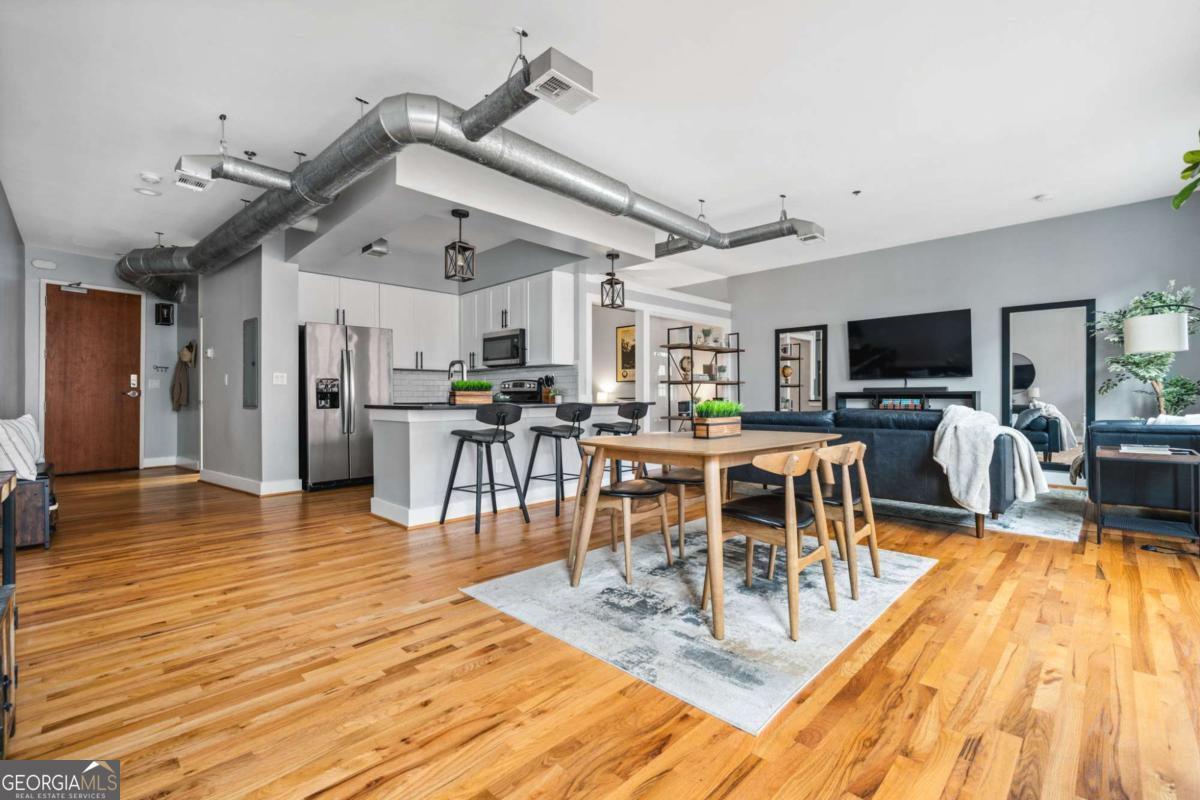 Experience the best of city living in this beautifully updated open-concept condo in the heart of Midtown! The modern kitchen features white shaker cabinets, stone countertops, stainless steel appliances, and a breakfast bar for casual dining. The dining area opens to a Juliette balcony through French doors, filling the space with natural light and offering an easy flow into the spacious living room. Gorgeous hardwood floors run throughout, adding warmth and style. The primary suite boasts a spa-like en-suite bath and a large walk-in closet, while a stackable washer/dryer adds everyday convenience. Relax or entertain on the updated rooftop deck with stunning views of the Midtown skyline, complete with a gas grill and seating area. Additional highlights include an assigned parking space in the secure gated garage and unbeatable proximity to all Midtown has to offer-Piedmont Park right in your backyard, The High Museum, Colony Square, Marta, and local favorites like Flying Biscuit and Caribou Coffee. Move-in ready and perfectly located, this condo combines comfort, convenience, and vibrant city living!