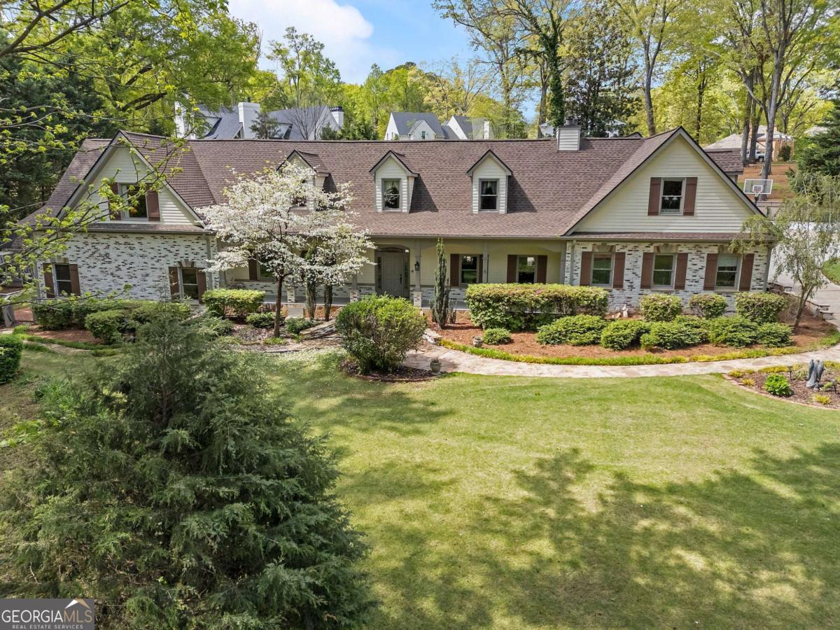 Experience the ultimate in multi-generational living on this private 1.26-acre estate, just a leisurely stroll from Historic Marietta Square or Kennesaw Mountain National Park. Thoughtfully renovated and designed with entertaining in mind, this spacious home boasts two master suites, Jack-and-Jill bedrooms, and a private nanny or in-law apartment conveniently serviced by an elevator. The bright, open living areas lead to a stunning veranda, complete with an outdoor fireplace and kitchen-perfect for entertaining against a serene backdrop of mature gardens and a level backyard ideal for adding a pool. The walkout terrace level features a media room and a wet bar with a pass-through window to the outdoor kitchen, ensuring seamless indoor-outdoor gatherings. The kitchen features a walk-in pantry/scullery, plus a two-car side-entry garage with an attached workshop, offering an abundance of practical space. Built by a custom homebuilder and impeccably maintained, the property also boasts recent updates such as a new roof. Don't miss this rare opportunity to own a legacy home brimming with thoughtful upgrades and timeless appeal.