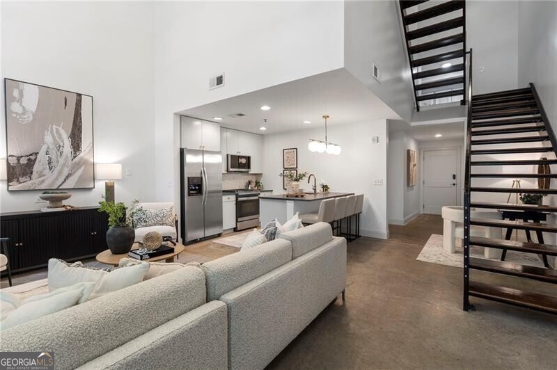 Modern luxury, refined finishes, and an unbeatable Midtown location converge in this exceptional ground-floor residence at the coveted 905 Juniper. Offering rare privacy and direct street-level access, this 2-bedroom, 1.5-bath home blends effortless convenience with elevated design-perfect for those who want to be in the heart of the city without sacrificing style or ease. Inside, floor-to-ceiling windows flood the open-concept living space with natural light, highlighting the clean lines and warm, inviting atmosphere. The recently renovated kitchen is a standout, featuring dramatic soapstone countertops, a marble backsplash, stainless steel appliances, custom cabinetry, and an oversized island that seamlessly connects cooking, dining, and entertaining. Throughout the home, designer lighting-including sophisticated fixtures from Visual Comfort-adds curated elegance and architectural interest. The spacious primary suite includes generous closet space and a spa-like bath with a soaking tub, glass-enclosed shower, and double vanity. The second bedroom offers versatility as a guest room, office, or flex space, and a well-placed half bath adds everyday convenience. This unit's unique location within the building allows for direct access to the main entrance, concierge, and street-level amenities without the need for an elevator-a major perk for pet owners, travelers, and anyone who values simplicity and ease. Elevator access brings you to the upper-level common spaces, including a resort-style saltwater pool and hot tub, state-of-the-art fitness center, and lush rooftop terrace. Additional highlights include a deeded parking space in the gated garage and a separate private storage unit-an often-elusive bonus in Midtown condo living. All of this is located just blocks from Piedmont Park, the Atlanta BeltLine, the Fox Theatre, MARTA, and Midtown's renowned dining, shopping, and cultural destinations. Whether you're seeking a sophisticated primary residence or the perfect lock-and-leave retreat, Unit 116 offers a rare opportunity to live beautifully in the heart of it all.