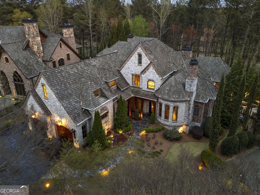 This exceptional European-inspired estate seamlessly blends elegance and functionality. Upon entry, you're welcomed by soaring ceilings, grand stone columns, and a balcony overlooking the spacious foyer. The fireside gentlemen's study features rich wood paneling, custom bookshelves, and a hidden storage room, while the formal dining room offers a perfect space for hosting dinner parties. The formal living room opens to a screened porch through floor-to-ceiling nano glass sliding doors, creating an effortless connection between indoor and outdoor spaces. The porch is equipped with a built-in gas grill and stone fireplace, ideal for year-round enjoyment. The expansive kitchen is a culinary dream, outfitted with Wolf appliances, including two dishwashers, three ovens, a warming drawer, and a large farm sink. It seamlessly connects to the breakfast area and family room, which includes a stone fireplace and a custom wooden bar with wine storage, an ice maker, and a wine fridge.The main-floor primary bedroom offers an indulgent retreat with an oversized fireplace, barrel-vaulted ceiling, and private balcony overlooking the tranquil backyard. The updated en-suite bathroom features a soaking tub, steam shower, dual vanities, and beautiful marble tiling. The walk-in closet is equipped with custom built-ins and an island for additional storage. Upstairs, a bonus room provides versatile space for a media room, play area, or home office. Four spacious bedrooms, each with a private bathroom and walk-in closet, complete the upper level. One oversized bedroom can serve as a secondary primary suite, offering a luxurious en-suite bathroom with marble countertops, a deep soaking tub, and a glass-enclosed shower. The terrace level is an entertainer's paradise. It includes a cozy den with a fully equipped kitchen and a stunning glass wine cellar, a home theater with built-in reclining seats and LED lighting, and a billiards area that opens directly to the back patio. The level also features a sauna and a private guest bedroom with its own bathroom and entry to the backyard. The downstairs back patio features nano sliding doors that open to the pool area, creating a smooth transition between indoor and outdoor living. With a gas fireplace, ceiling fans, and the option to enclose the space for year-round use, the patio is perfect for any season. Adjacent to the patio, a built-in gas grill and stone fire pit area enhance the outdoor living experience. The backyard is a true highlight, featuring a soaking hot tub with a waterfall that flows gently into the pool, pool lighting for evening swims, and a tanning ledge for sunny days. A manicured grassy yard runs parallel to the pool deck, balancing lush greenery with open space. Located at the end of a cul-de-sac in the prestigious gated community of Ardsley Park, this home is as impressive inside as it is outside.This estate provides the perfect combination of comfort, style, and entertainment, making it truly one of a kind.