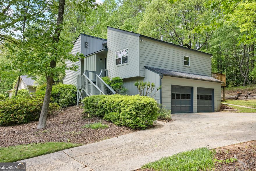 Charming Cedar Contemporary in Coveted Chimney Springs. Welcome to this beautiful 4-bedroom, 2-bath cedar contemporary nestled in one of East Cobb's most beloved neighborhoods Chimney Springs. With Hardi Plank siding offering a low-maintenance exterior and mature azaleas bursting with seasonal color, this home delivers both curb appeal and low maintenance. Inside, you'll find brand-new hardwood floors that flow throughout the main living areas, including a thoughtfully updated kitchen featuring double ovens, a modern vent hood, new stainless appliances, quartz counters, and a rolling island for added versatility. A sliding glass door off the kitchen opens onto a spacious back deck, where you can enjoy serene views of your private, wooded backyard. The heart of the home is the expansive family room, complete with soaring cathedral ceilings, a cozy fireplace, and transom windows that flood the space with natural light. Entertain effortlessly with a wet bar and direct access to the back deck. The formal dining room, just off the foyer with an expanded doorway, accommodates large gatherings perfect for hosting up to 25 guests during holidays and special events. Upstairs, the owner's suite is a private retreat with a large walk-in closet and private deck access overlooking the backyard. The ensuite bath features a partially updated design with a separate stone and glass surround shower. The lower level offers two additional guest bedrooms and a full guest bath, while the lowest level boasts a flexible fourth bedroom ideal as a media room, home office, or private guest space. Living in Chimney Springs means enjoying a lifestyle enriched with outstanding community amenities, including an Olympic-sized swimming pool, clubhouse, tennis, pickleball, and basketball courts, a lake with scenic trails, playground, and a large open field perfect for team sports and outdoor fun. With its thoughtful updates, functional layout, and access to resort-style amenities, this Chimney Springs gem is ready to welcome you home.