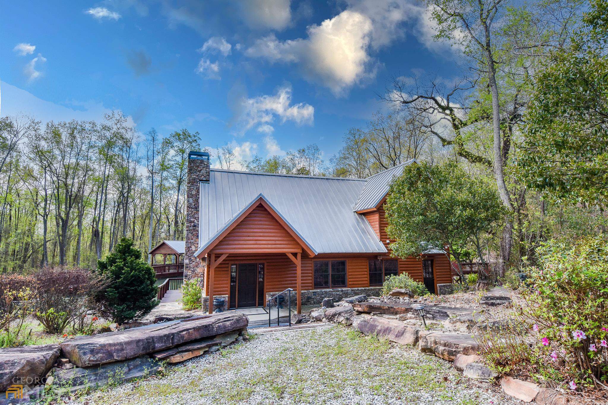 An amazing opportunity to own this storybook mountain resort in the heart of Ga! Down the long gravel driveway you will find a one of a kind true log cabin with stunning, custom workmanship throughout. Vaulted tongue and grove ceilings in the open floor plan go perfectly with the large, stacked stone, wood burning fireplace. Large handmade dining table right next to kitchen with refreshing natural daylight. The cabin offers two large en suite bedrooms with walk in cedar closets , one upstairs and one down. Walk out to the huge covered back porch to the captivating outdoor amenities such as the spring fed pond with walk around access, covered and uncovered patios to enjoy and the soothing waterfall that sets this place apart! Complete with your own private event space with kitchen to host all your friends and family. The cabin also comes fully furnished. All this thoughtfully nestled in on over 700 acres of breathtaking views and prime hunting land! Come ride the cut roads to view the wildlife and nature at it's finest. Many possibilities for this property, would make the perfect hunting retreat and Air BnB. Come make this retreat yours today!