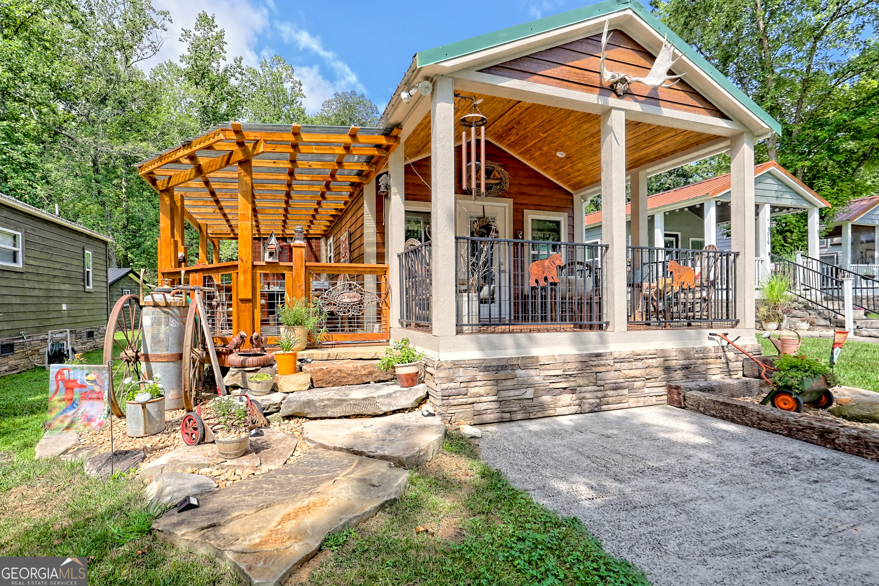 Charming and low-maintenance, this cozy home at Sugar Mill Creek is designed for comfort, relaxation, and outdoor living. Large natural stone boulder steps lead to covered porches that welcome you and your guests. Inside, enjoy warm wood finishes, a cozy fireplace, and a thoughtfully designed kitchen with a double stainless sink, dishwasher, washer/dryer, pantry, and counter top seating. The expanded bedroom includes a 7' clothes closet with mirrored slider doors. The office area opens up to a private deck thru the glass sliding door. the deck leads to a 6 person hot tub and an outdoor kitchen counter with custom cabinets and outdoor dining area. A detached shed offers a workbench, wardrobe, and tool storage-plenty of space for your gear. The backyard is your personal haven, featuring a babbling brook, hammock, shade trees, and a stone fire pit-perfect for unwinding. Located in the gated, resort-style community of Sugar Mill Creek at Lake Burton, you're just minutes from local favorites like Bleu Canoe, Laprades Marina with four restaurants, hiking trails, waterfalls, and Lake Burton itself. Conveniently situated between Clayton, Helen, and Clarkesville, this is mountain living at its best-ideal for full-time residence or peaceful getaways. Come experience the perfect blend of serenity, adventure, and community. Since the owners occupied the residence part-time in the summer, the home looks pristine.