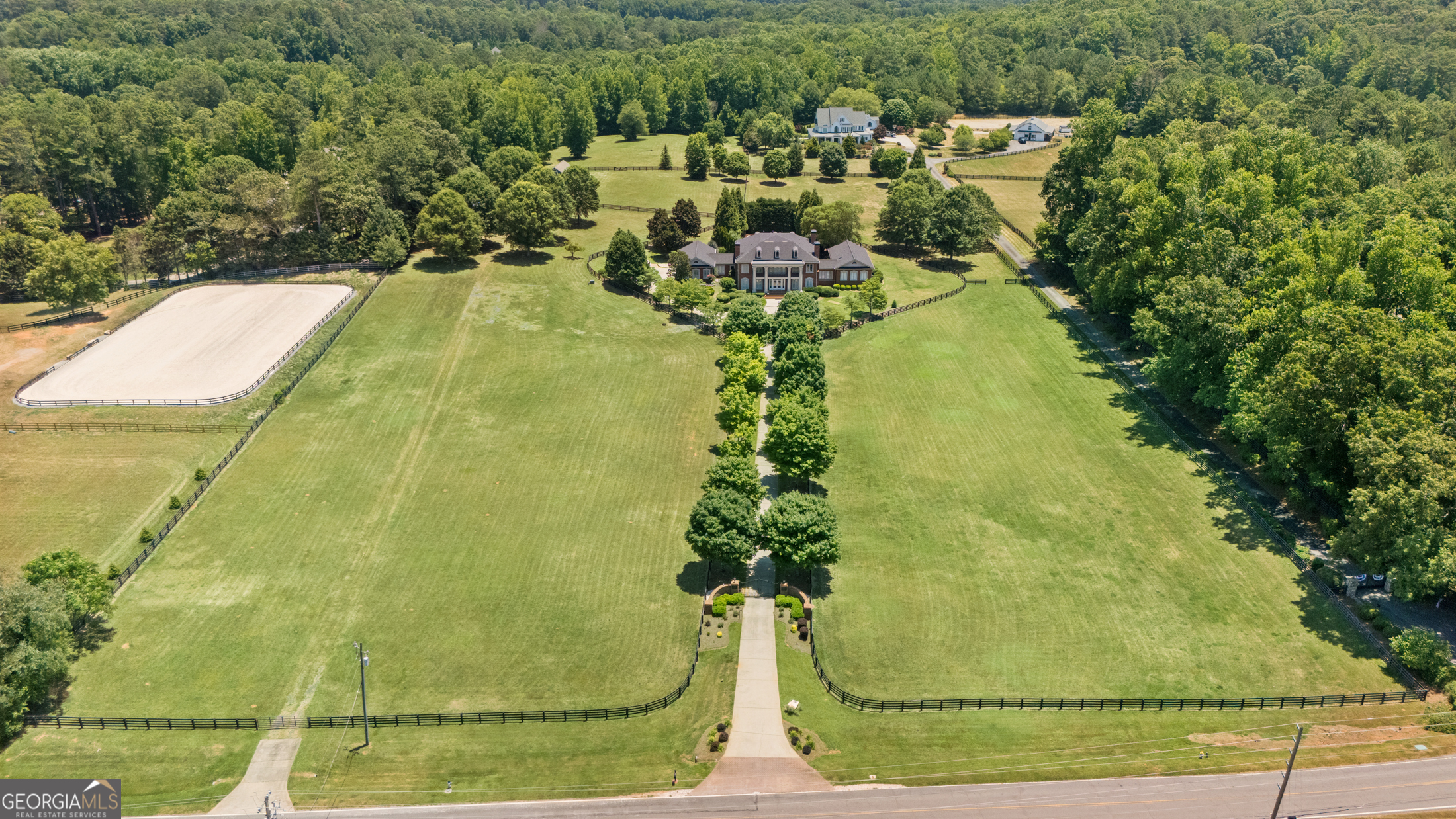 Welcome to Freemanville Estates. Situated in the center of an expansive 9.72-acre lot, this property offers a luxurious and private retreat in the heart of Milton's horse country. This elegant home is situated in the center of the property with 4 large flat paddocks. As you arrive through the private gated entry you're greeted by the home's stately columns and beautiful upper balcony creating endless curb appeal and charm. Step into the grand 2-story foyer adorned with beautiful tile floors and an enchanting chandelier, creating a captivating first impression. Adjacent to the foyer, you'll find a beautiful office space with a fireplace. The interior boasts multiple sitting rooms and a separate dining room, ample space for entertaining and relaxation. This home features two owner's suites, with one located on the main level and another on the upper level. The lower level owner's suite is thoughtfully set in a separate wing of the house, offering privacy and convenience. The owners bathroom is updated with marble tile and Jado gold plated fixtures. The upper level owner's suite is a true sanctuary, complete with a fireplace, balcony overlooking the pool, a grand large ensuite bathroom with double vanities, a separate shower, and tub. The eat-in kitchen is open to the main living room and is equipped with stainless steel appliances, a large island, and direct access to the pool and covered patio - creating the perfect space for relaxing and entertaining. Unwind with a bowl of popcorn & some friends in the 12 person movie theatre or step outside to discover the expansive patio, large pebble tech pool, fire pit, two courtyards, providing an idyllic setting for outdoor entertaining. Additional features include new roof, new paint throughout, surround sound, video surveillance and 3 car attached garage with large office space off the garage. Two additional buildings located on the property are equipped with water and power - climate controlled 40x50 building perfect for storing 8+ cars or great workshop and newly painted barn with 4 stalls, w/wash rack and tack/feed room. Additionally, the barn includes an unfinished upstairs room that presents the opportunity for additional living/working space. This property is situated directly across from the new Freemanville-Birmingham green space/equestrian park - 21 acres of pasture-like terrain. The land around the home provides ample space for privacy, and is wonderful for horses or other animals. Truly a special property with the park across the street, just minutes from everything Milton & Alpharetta have to offer - White Columns Golf & Country Club, 7 acres Bar & Grille, Scottsdale Farms, and so much more.